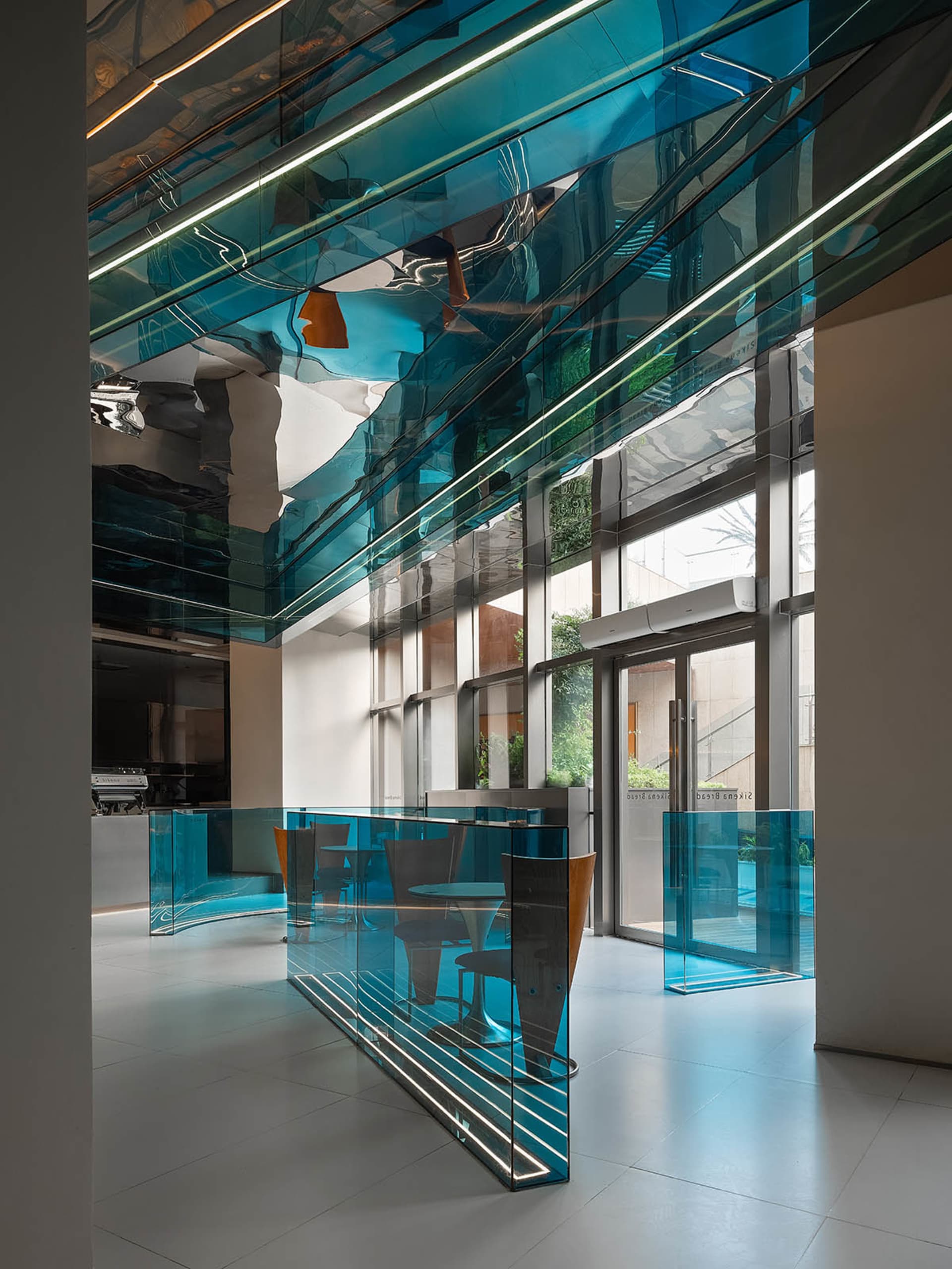 A modern cafe interior featuring glass walls and concrete flooring.
