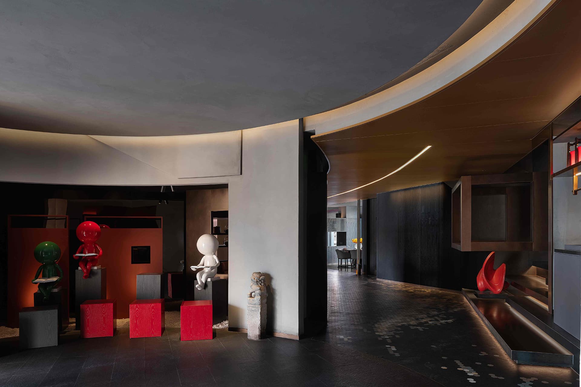 Modern lobby with concrete walls, black tiles, and red stools.