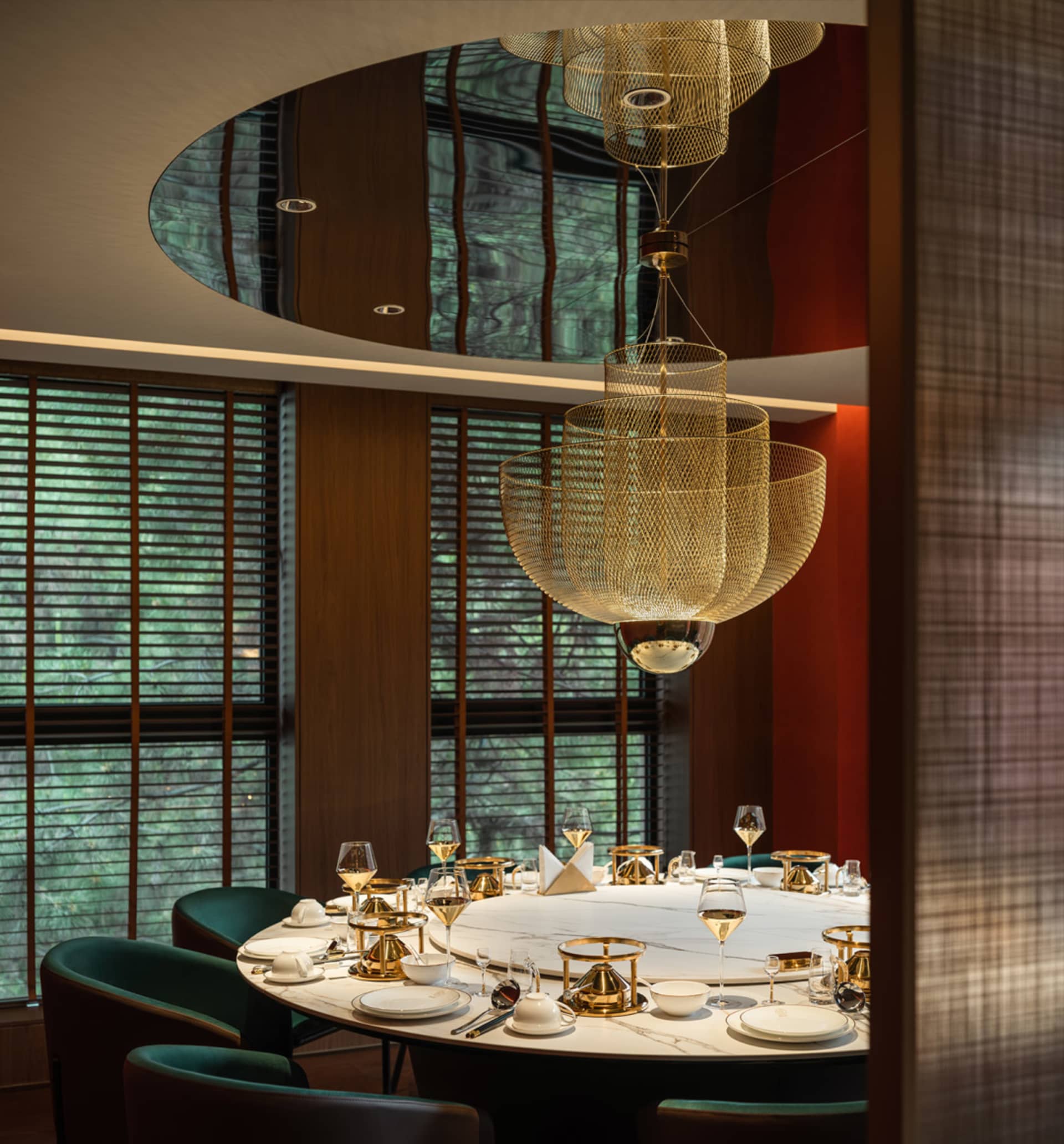 A modern restaurant interior with a round table, brass accents, and marble finishes.