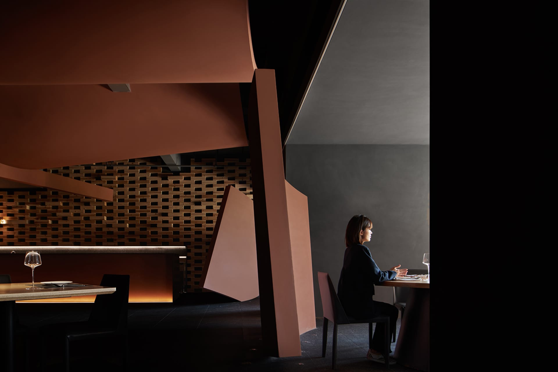 A modern restaurant interior featuring concrete walls and wooden tables.