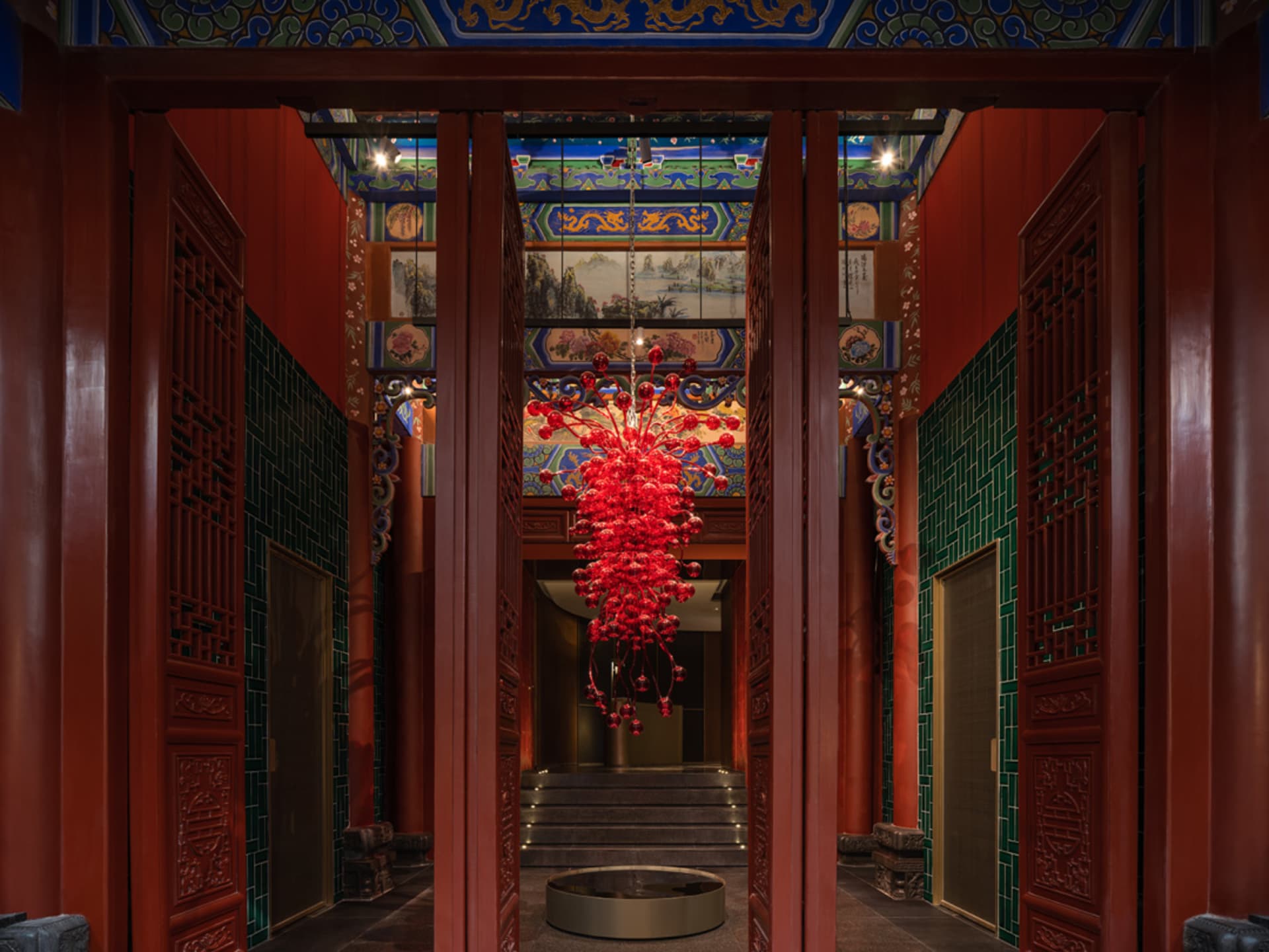 A red metallic chandelier hanging from the ceiling in a stylish interior design setting.