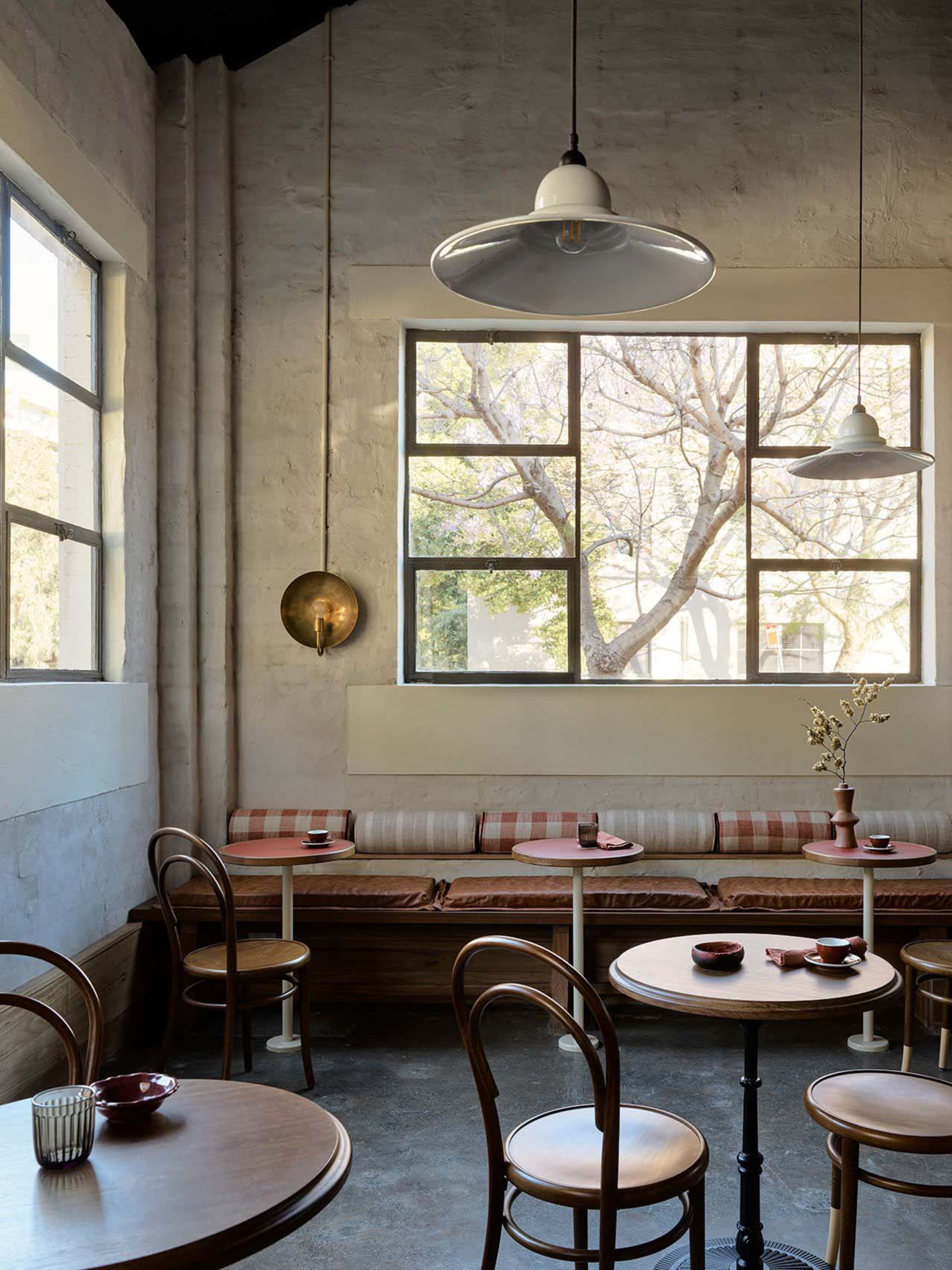 A cafe interior with wooden tables, metal chairs, and glass pendant lights.