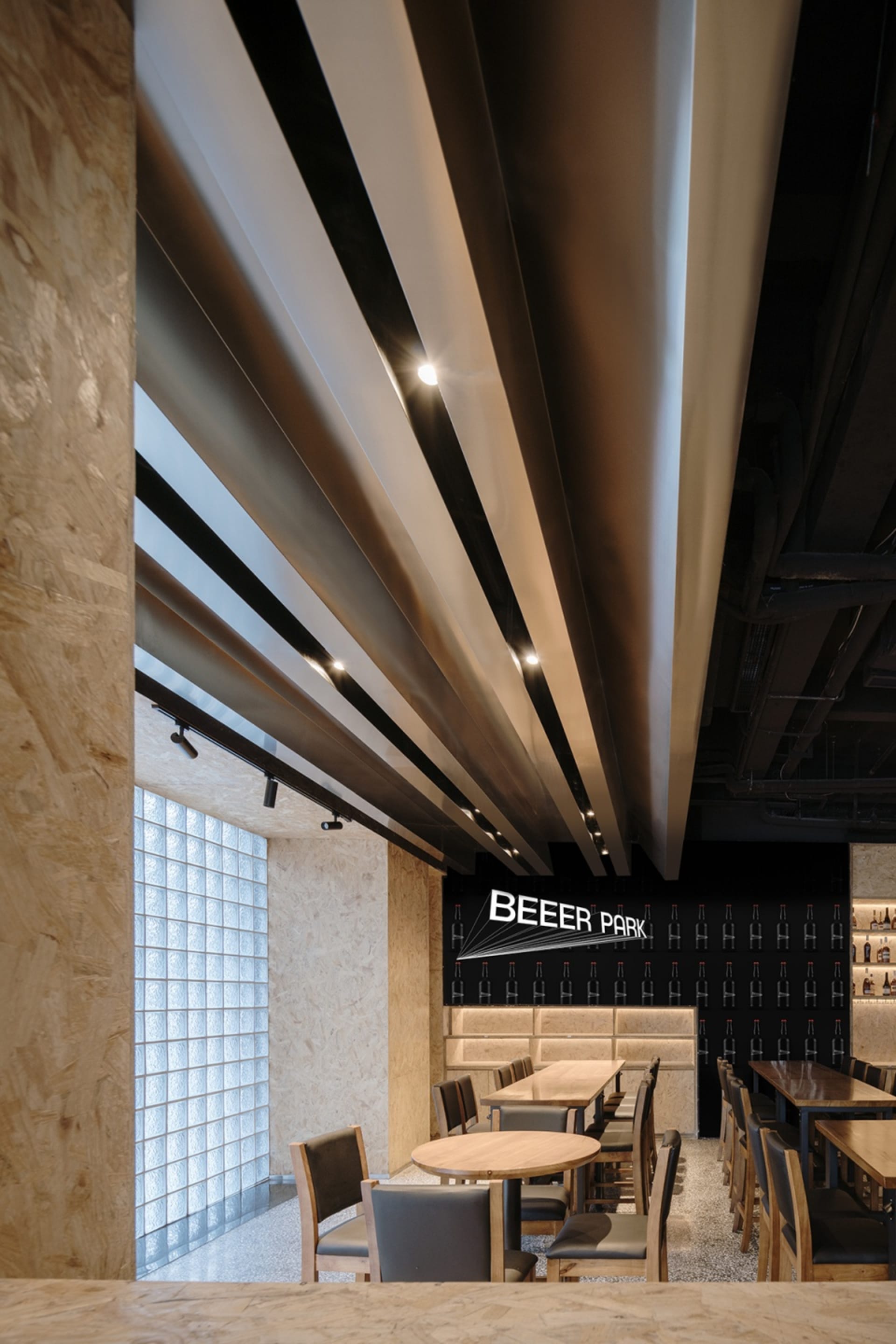 現代工業風餐廳室內,設有金屬橫樑天花板、木質餐桌以及俐落黑色點綴。