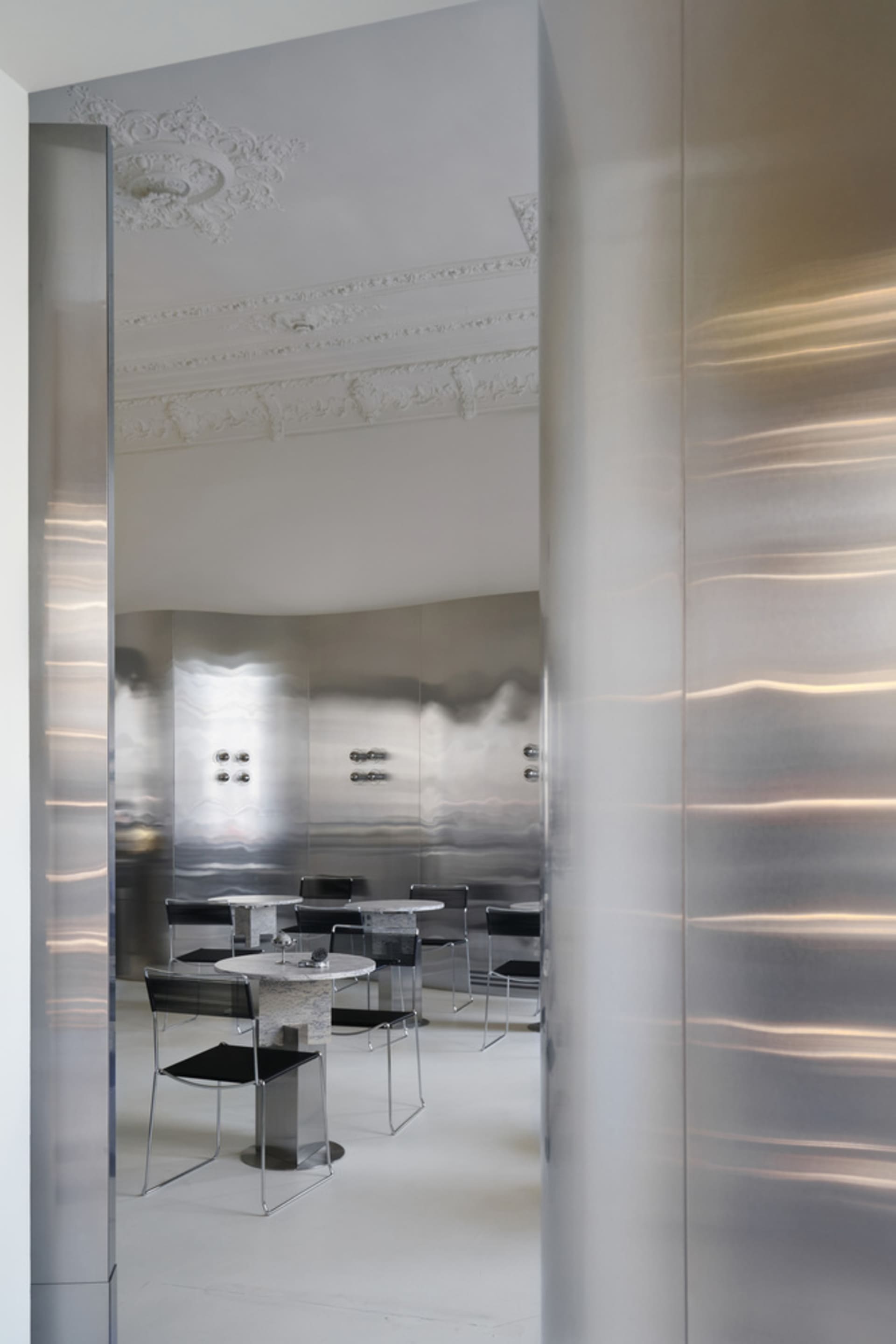 Minimalist restaurant interior with silver steel walls and tables and chairs.
