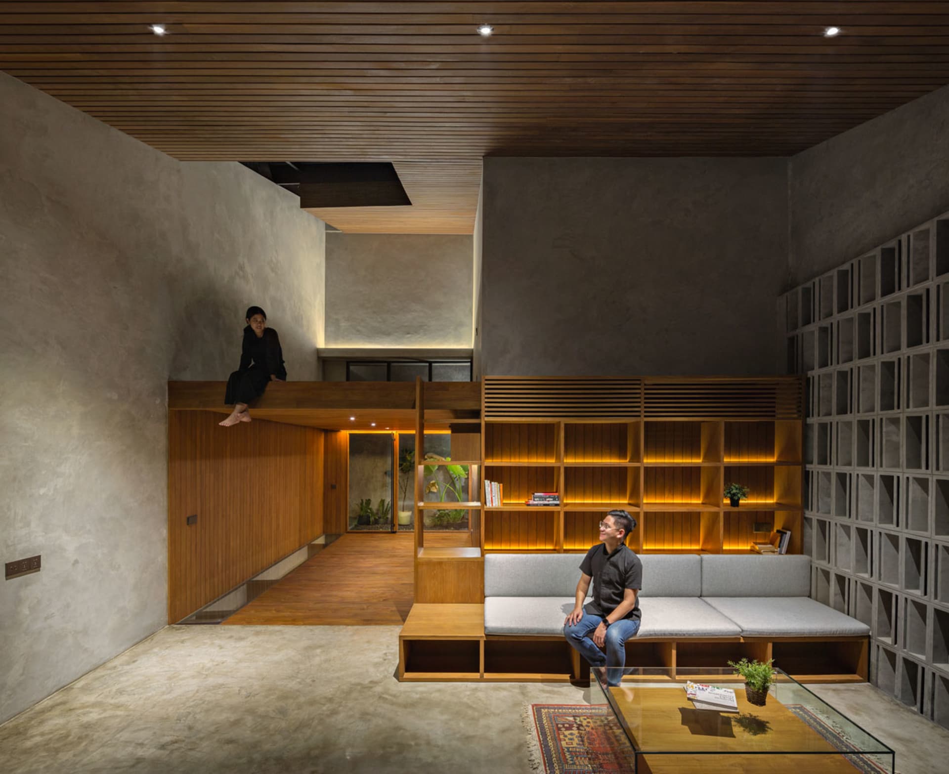 A modern living room with wooden shelves, a concrete floor, and a concrete wall.