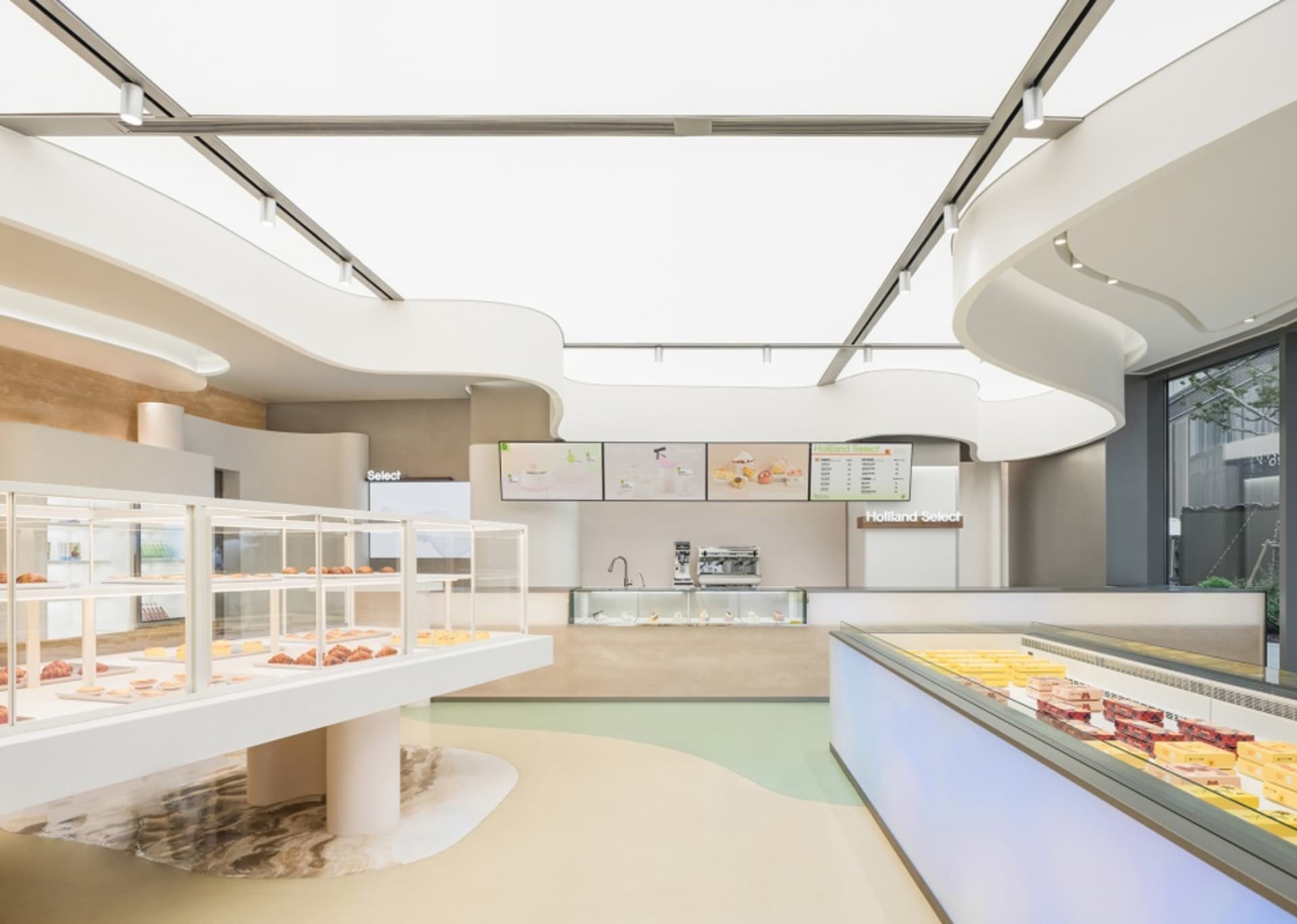 現代烘焙店採用白色混凝土室內設計，貨架陳列各式糕點，櫃台展示蛋糕。