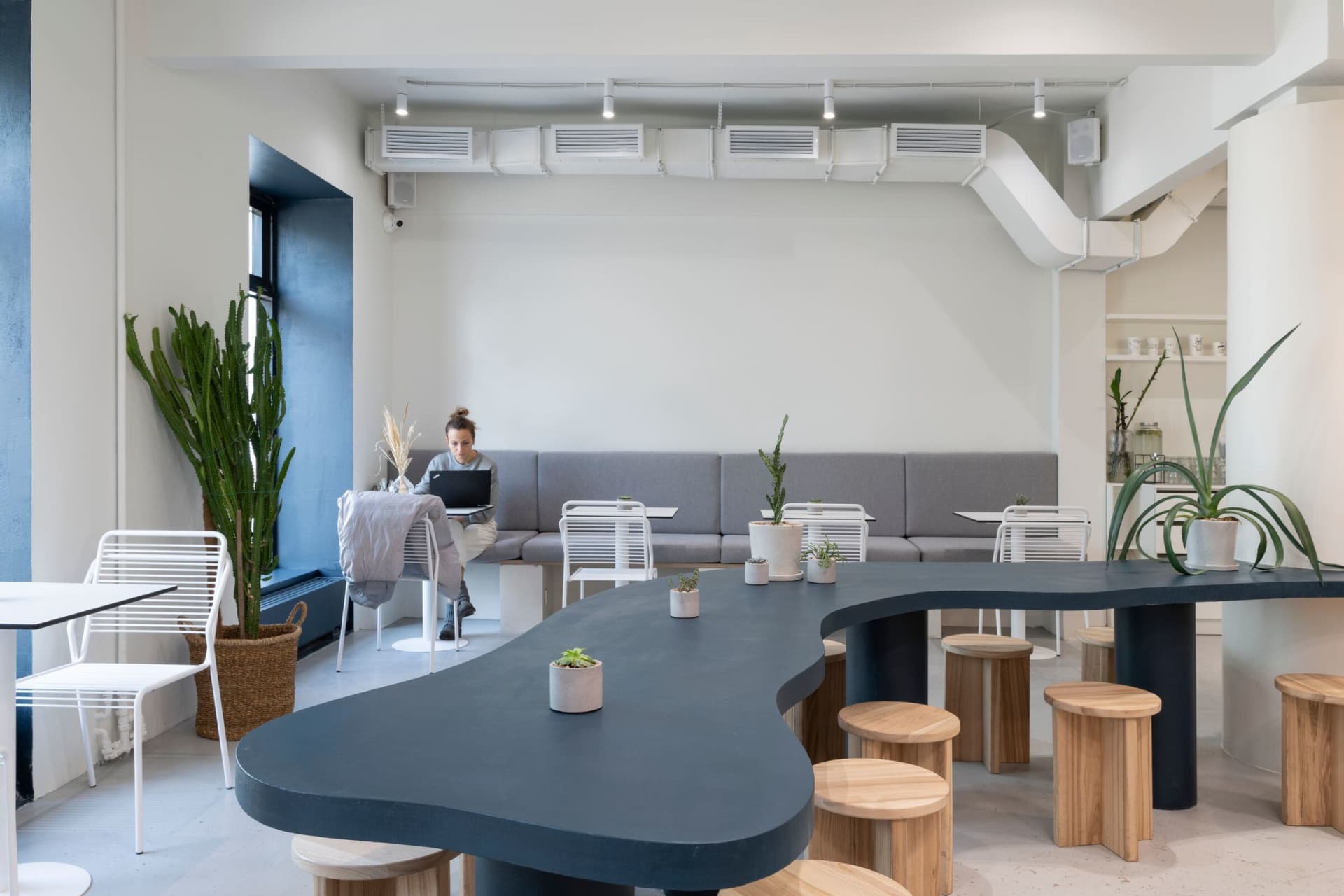 A modern cafe interior featuring minimalist furniture and a combination of concrete and wood materials.