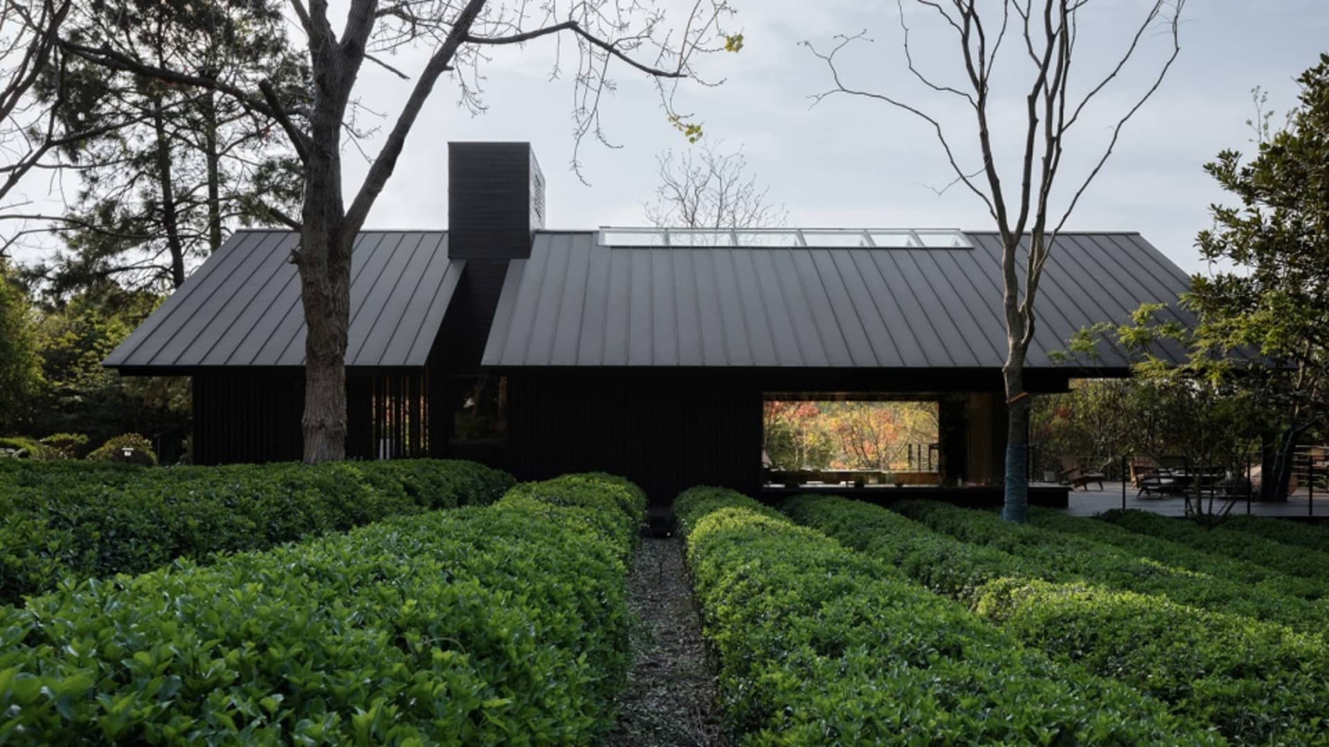 A modern residential building with metallic exterior and greenery surrounding it.