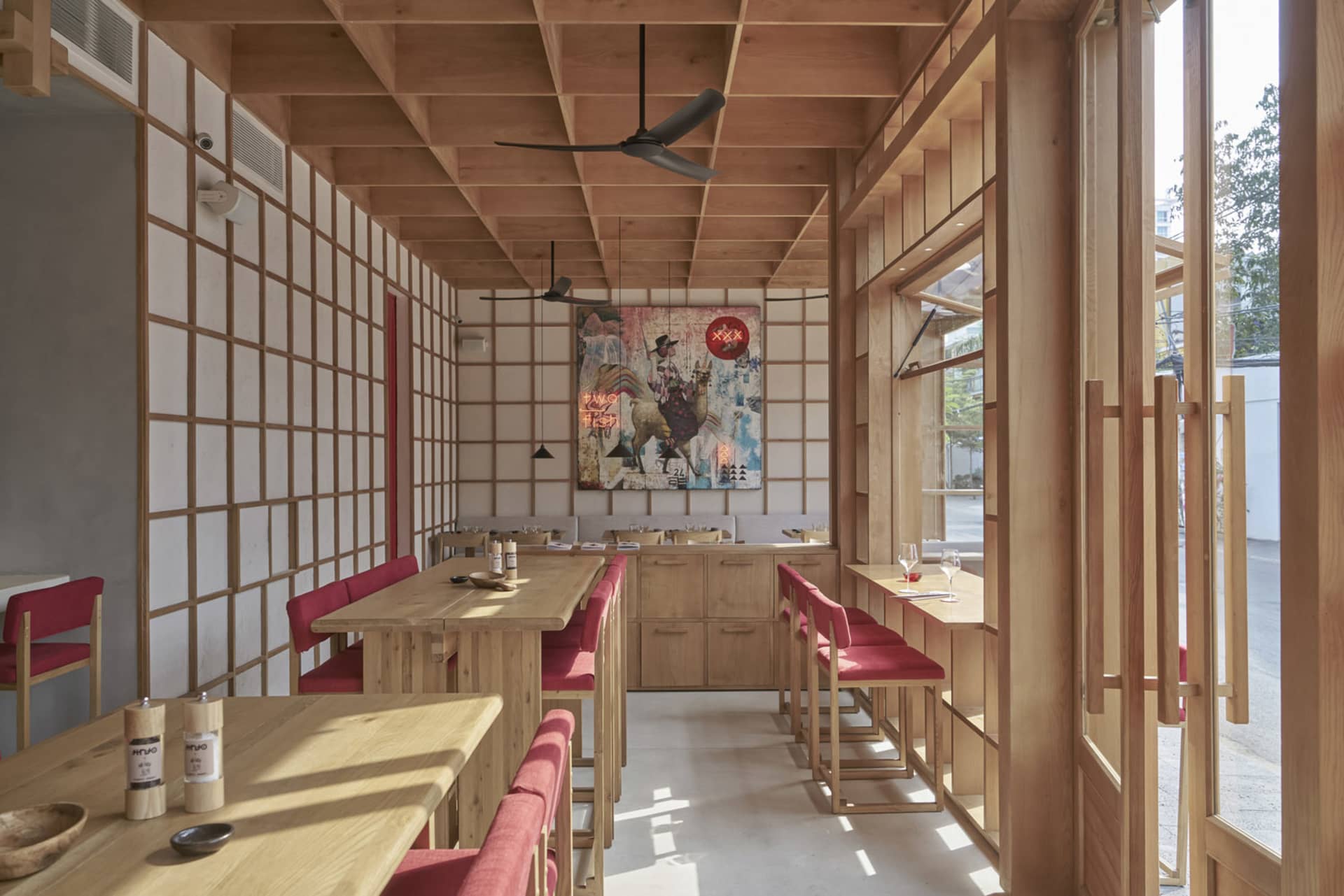 現代餐廳室內空間,搭配木質家具、彩色壁畫與紅色座椅。