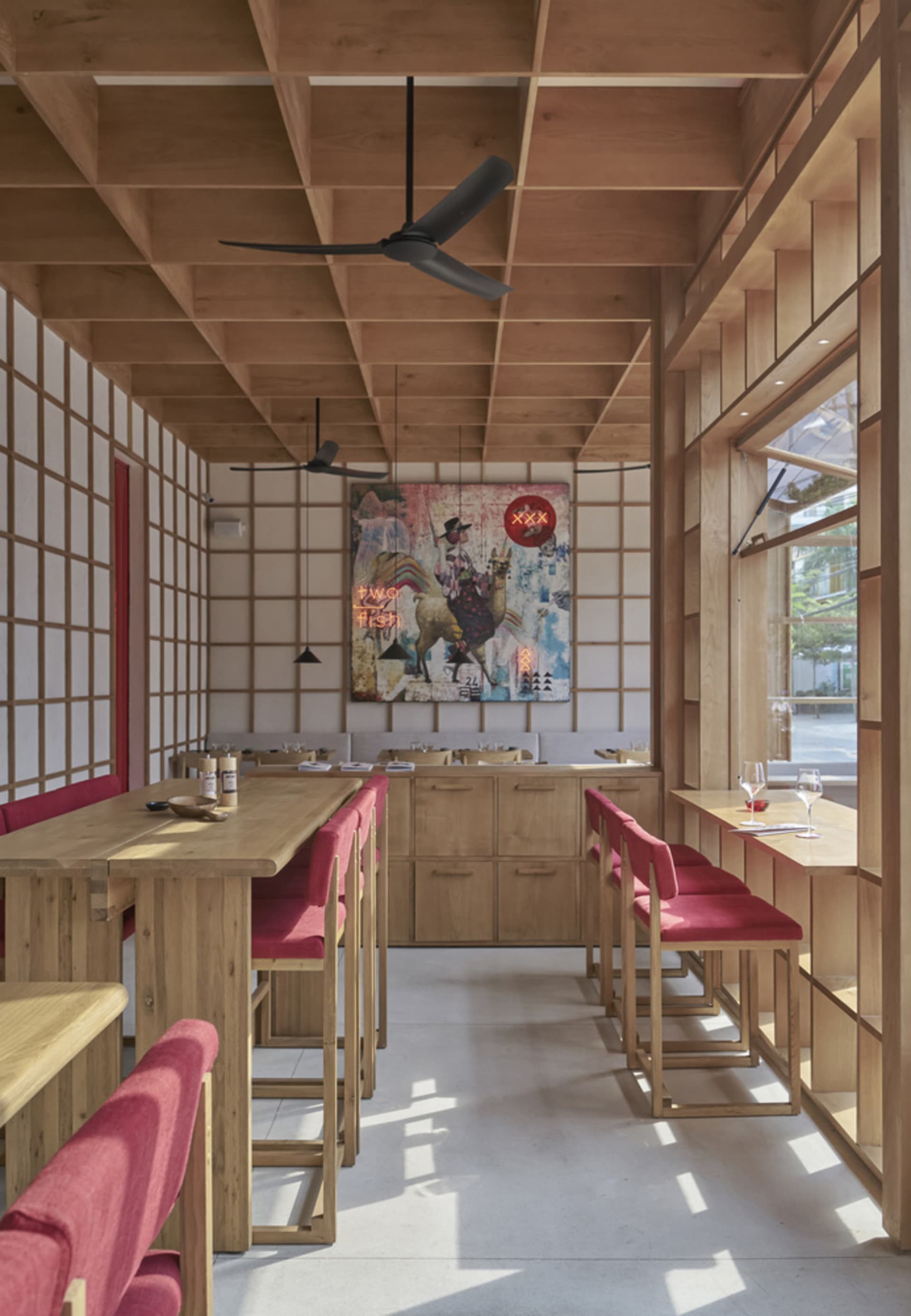 Modern restaurant interior with wooden furniture and vibrant artwork.