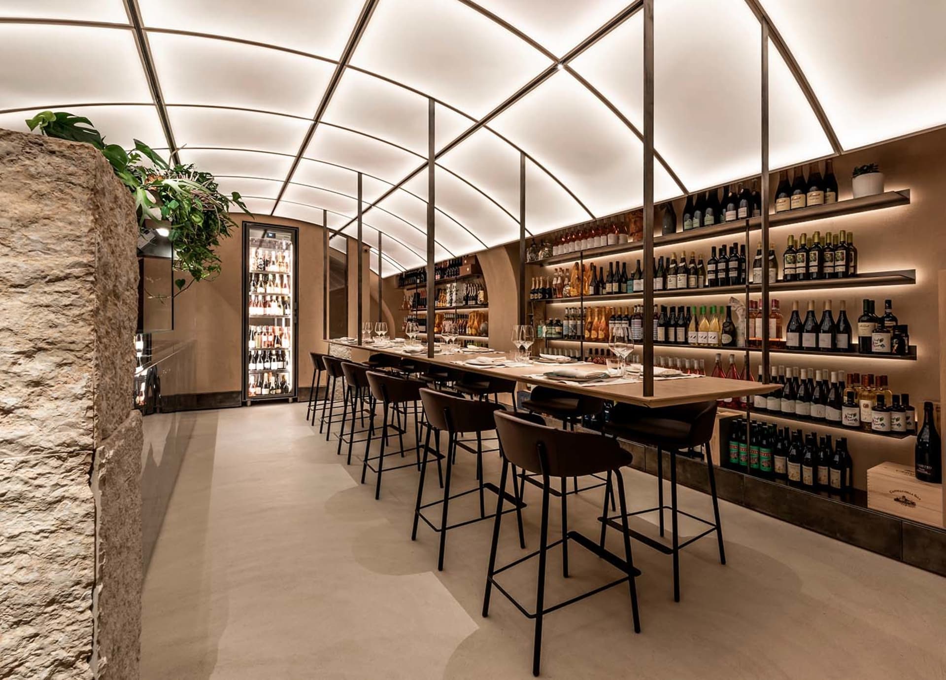 A modern restaurant bar with high ceilings, glass walls, and stone accents.