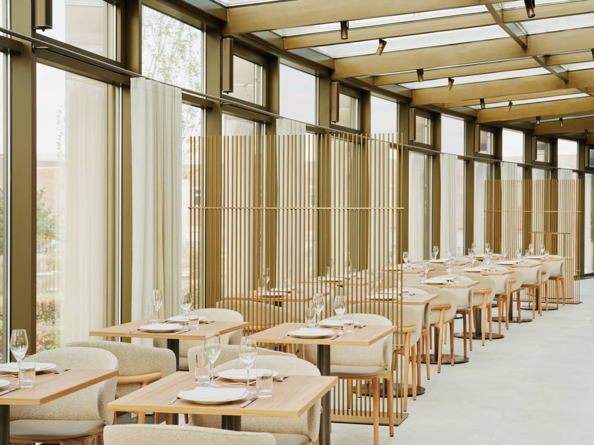 現代餐廳室內,搭配木質餐桌、玻璃隔間與布料座椅。