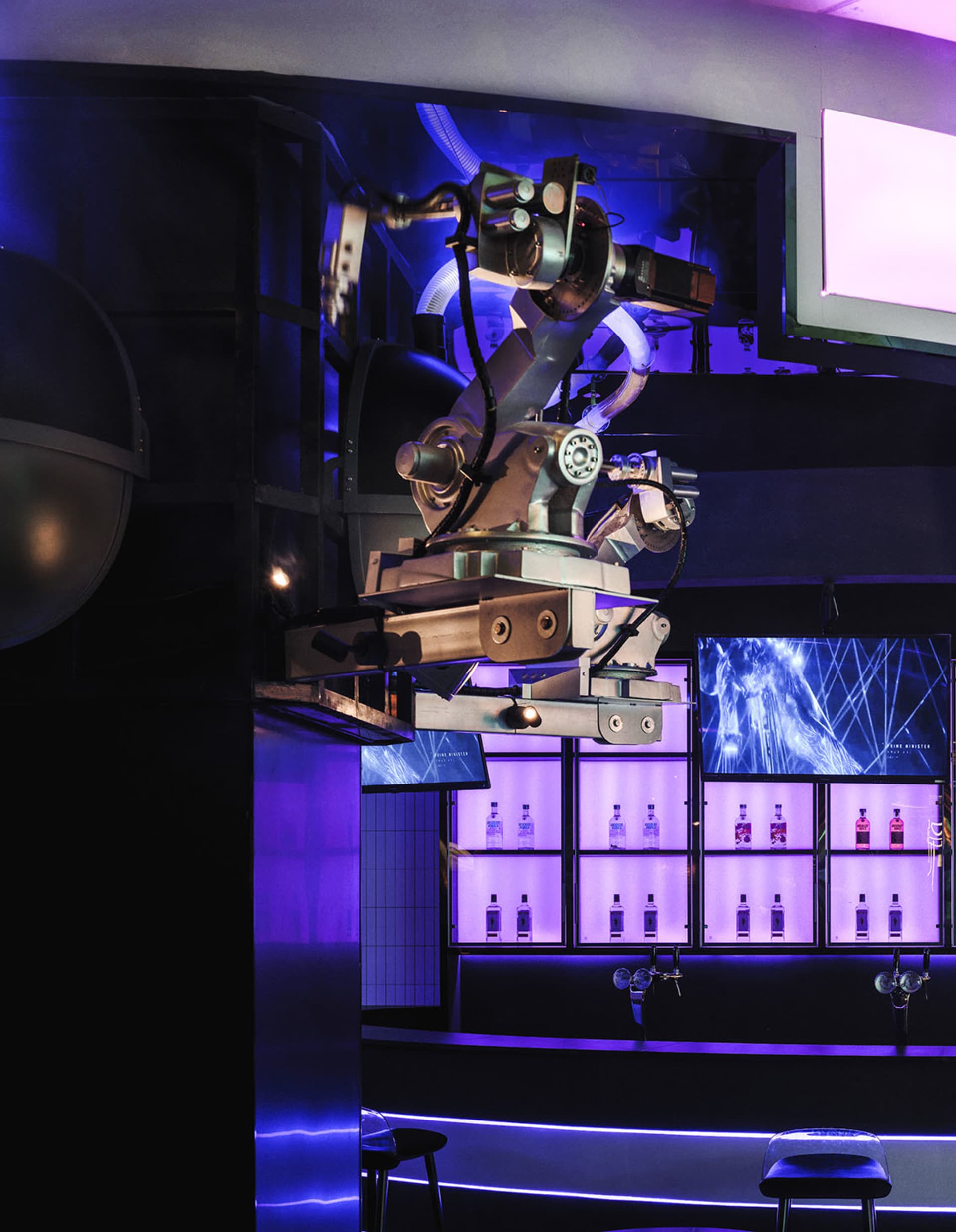 Modern industrial bar interior with metallic structures, glass panels, and LED lighting.