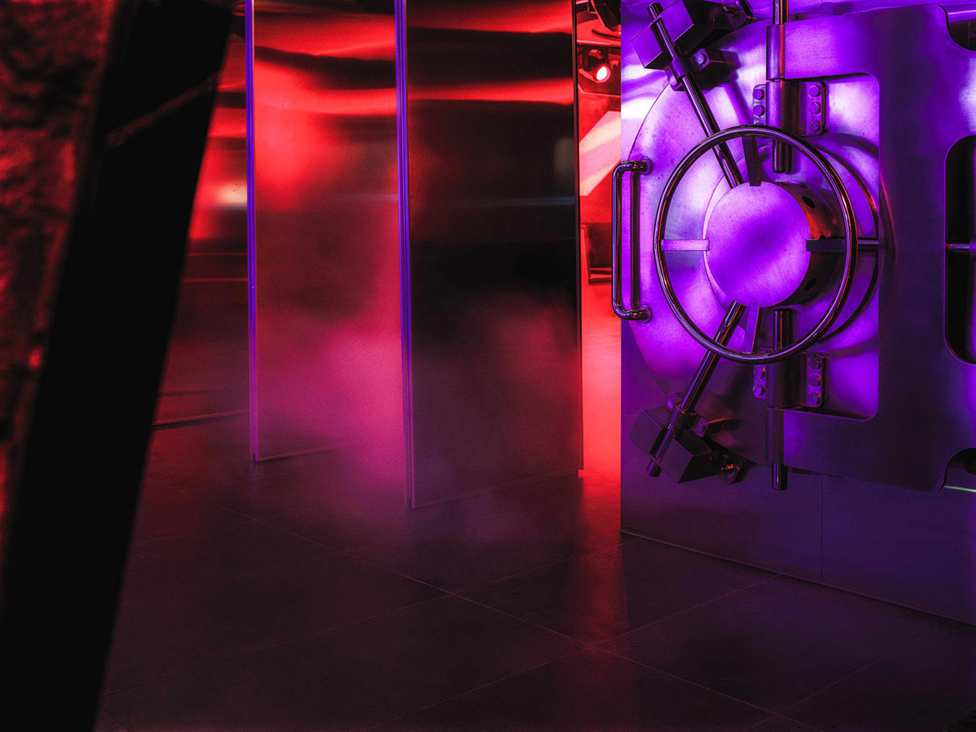 A modern bank vault illuminated with purple lighting and featuring metallic materials.