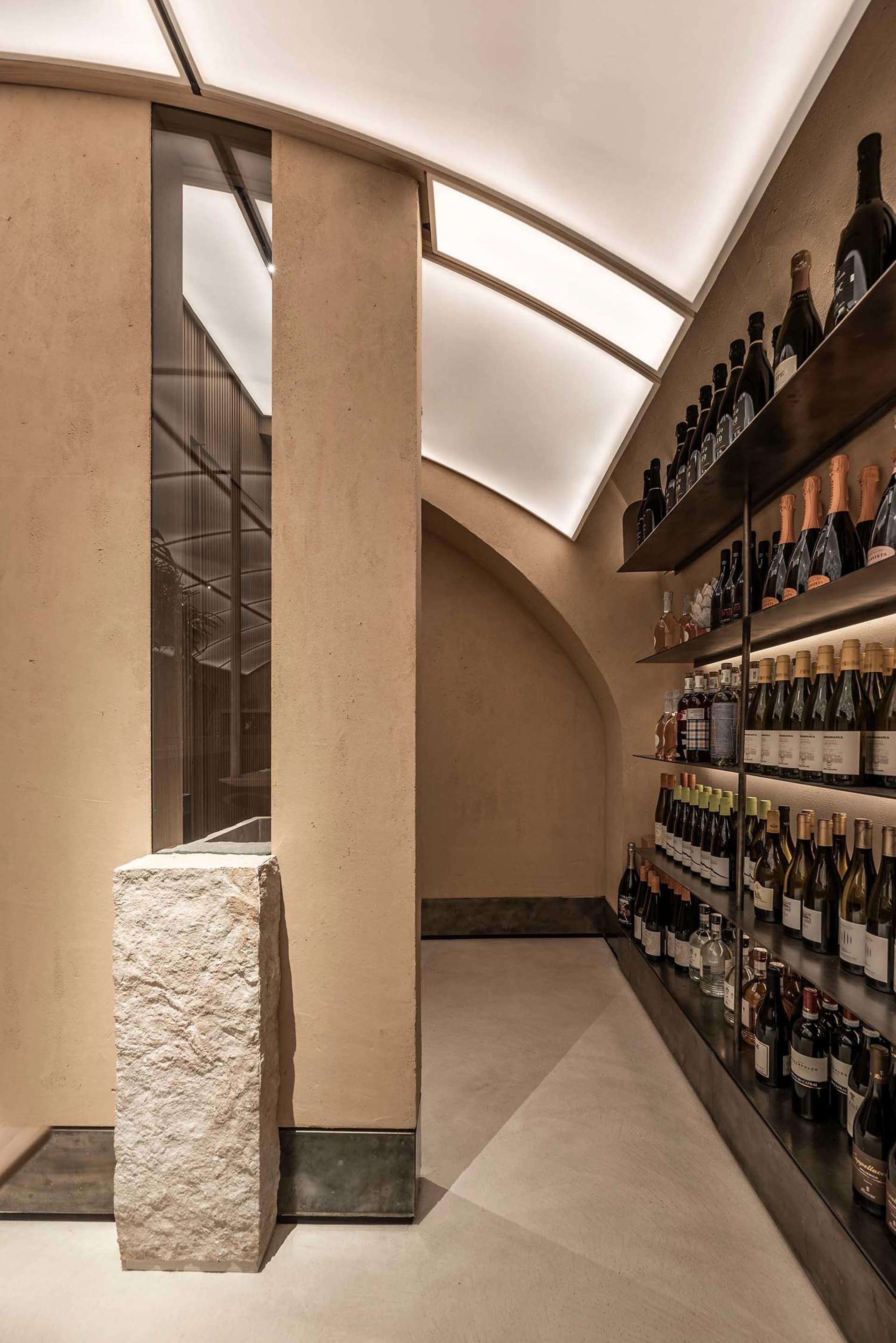 Modern wine tasting room with concrete walls, glass shelves, and metallic accents.