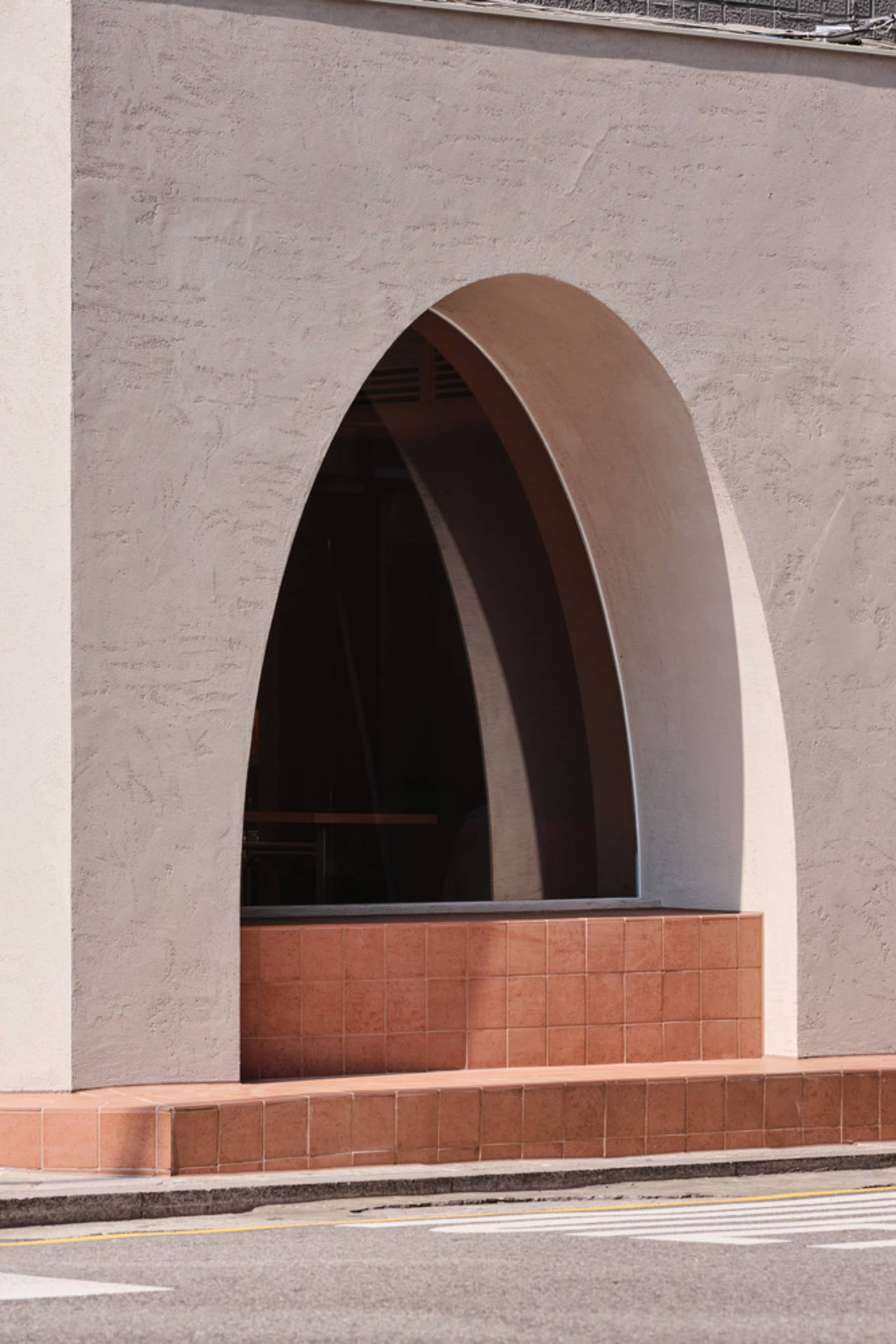 A concrete entryway with an arched opening and tiled bench seating.