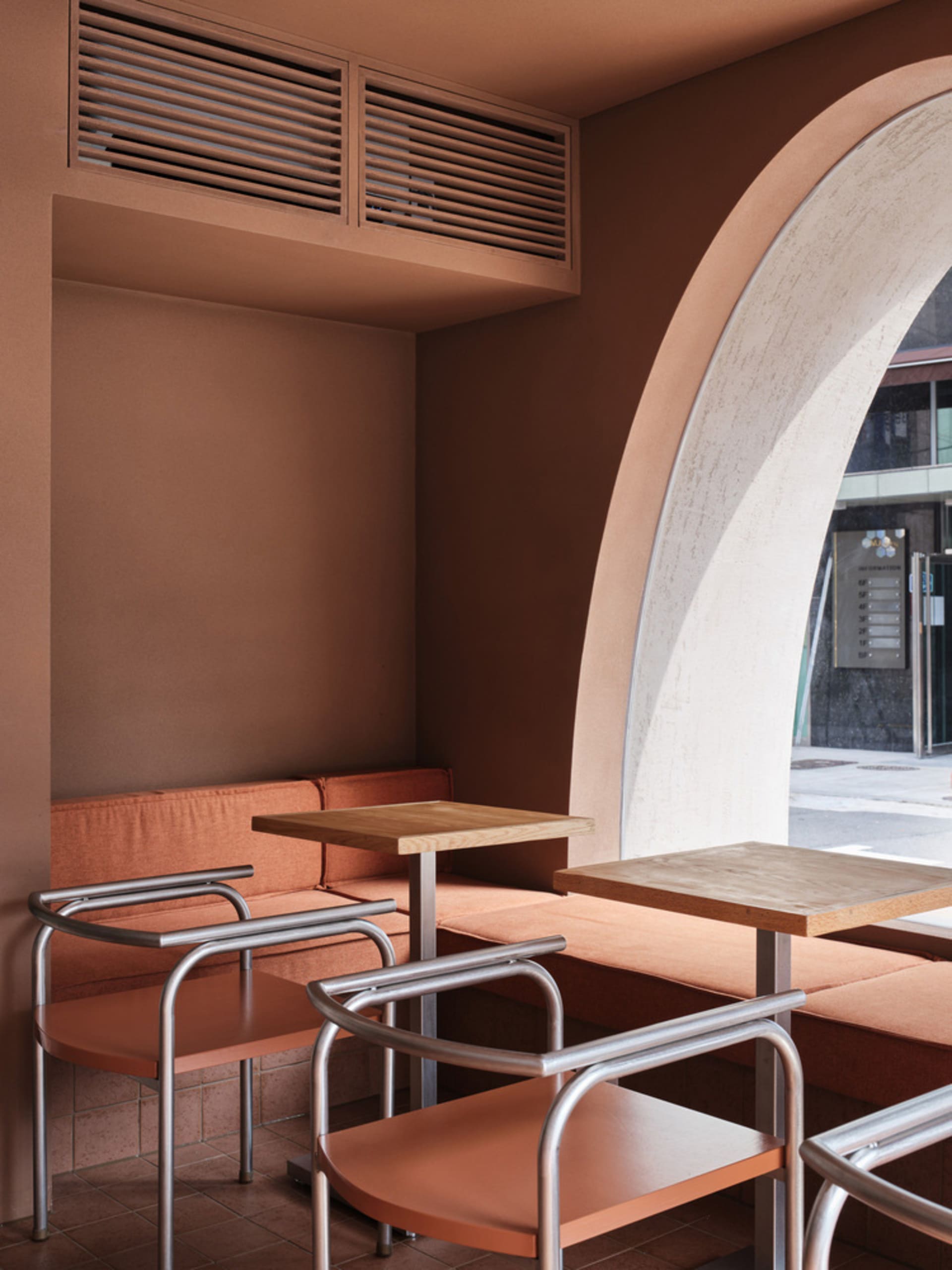 Modern cafe interior with terrazzo accents, wooden tables, and curved seating.