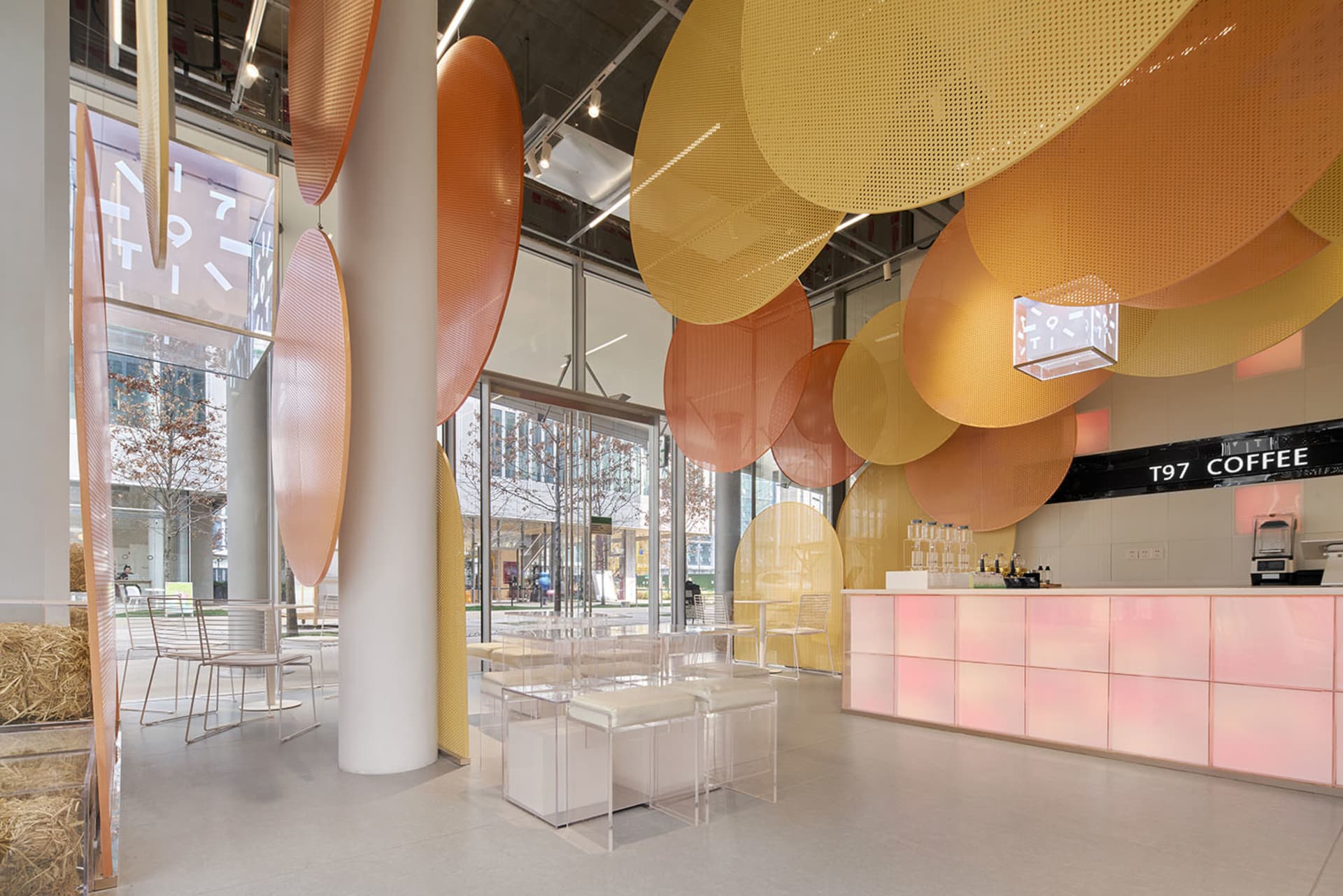 Interior of a modern coffee shop featuring a glass ceiling with geometric shapes.