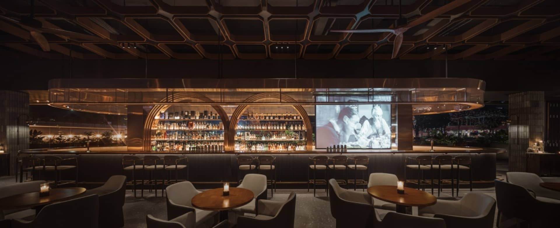 Modern metallic bar interior with arches and a large projection screen.