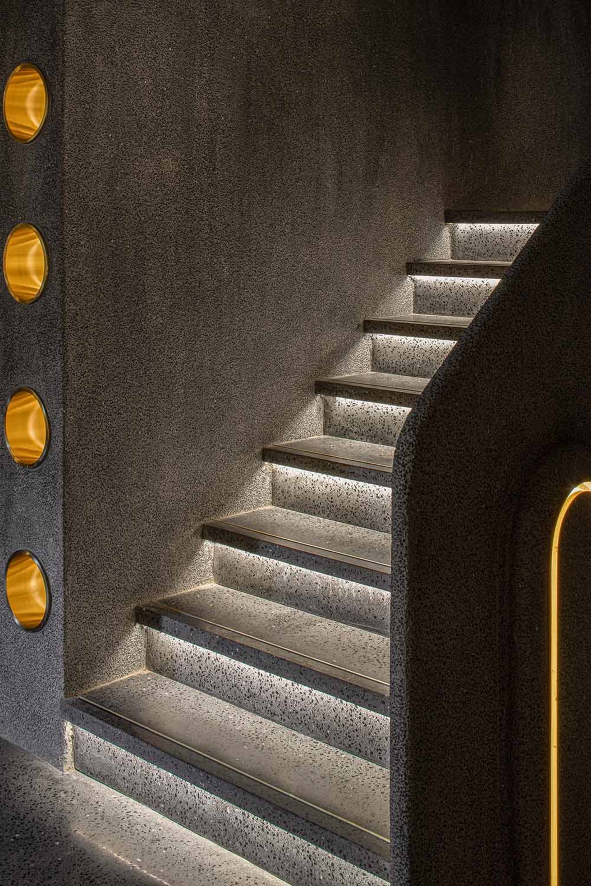 A modern staircase with concrete steps illuminated by built-in lighting.
