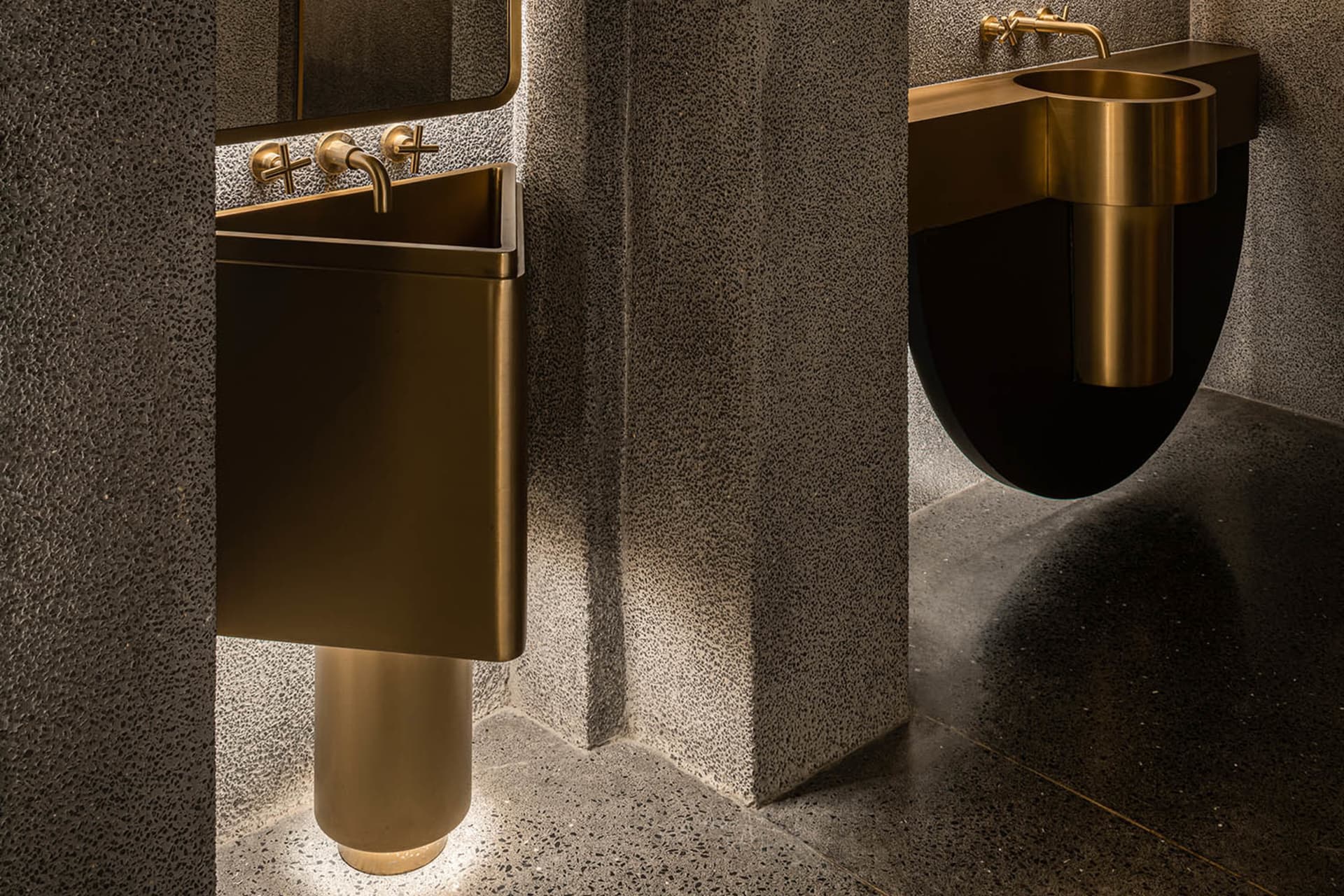 Modern industrial bathroom with metallic sinks and metallic fixtures.