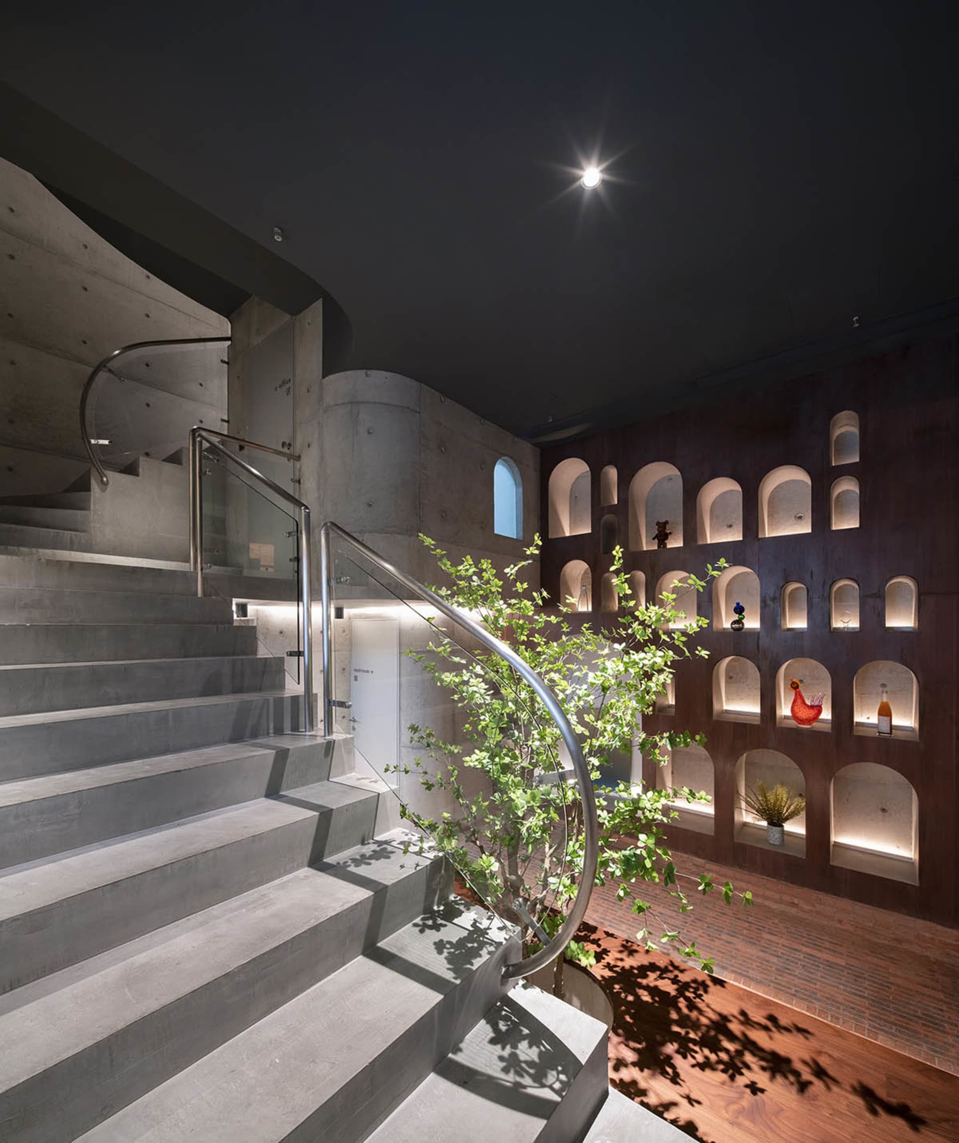 Industrial-style concrete staircase with glass railings and a plant