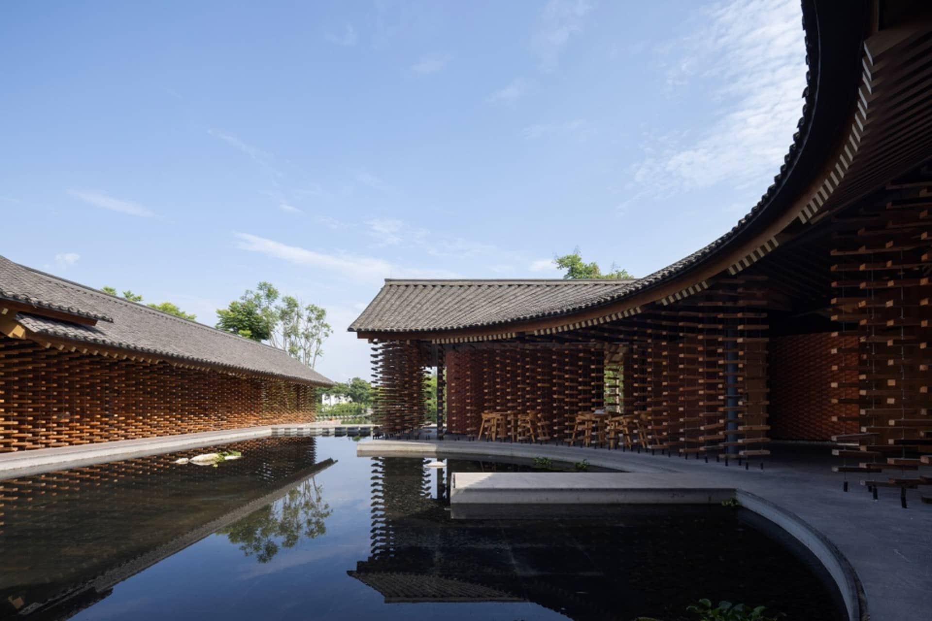 Modern architectural design featuring wooden structures and a reflective water feature in a public space.