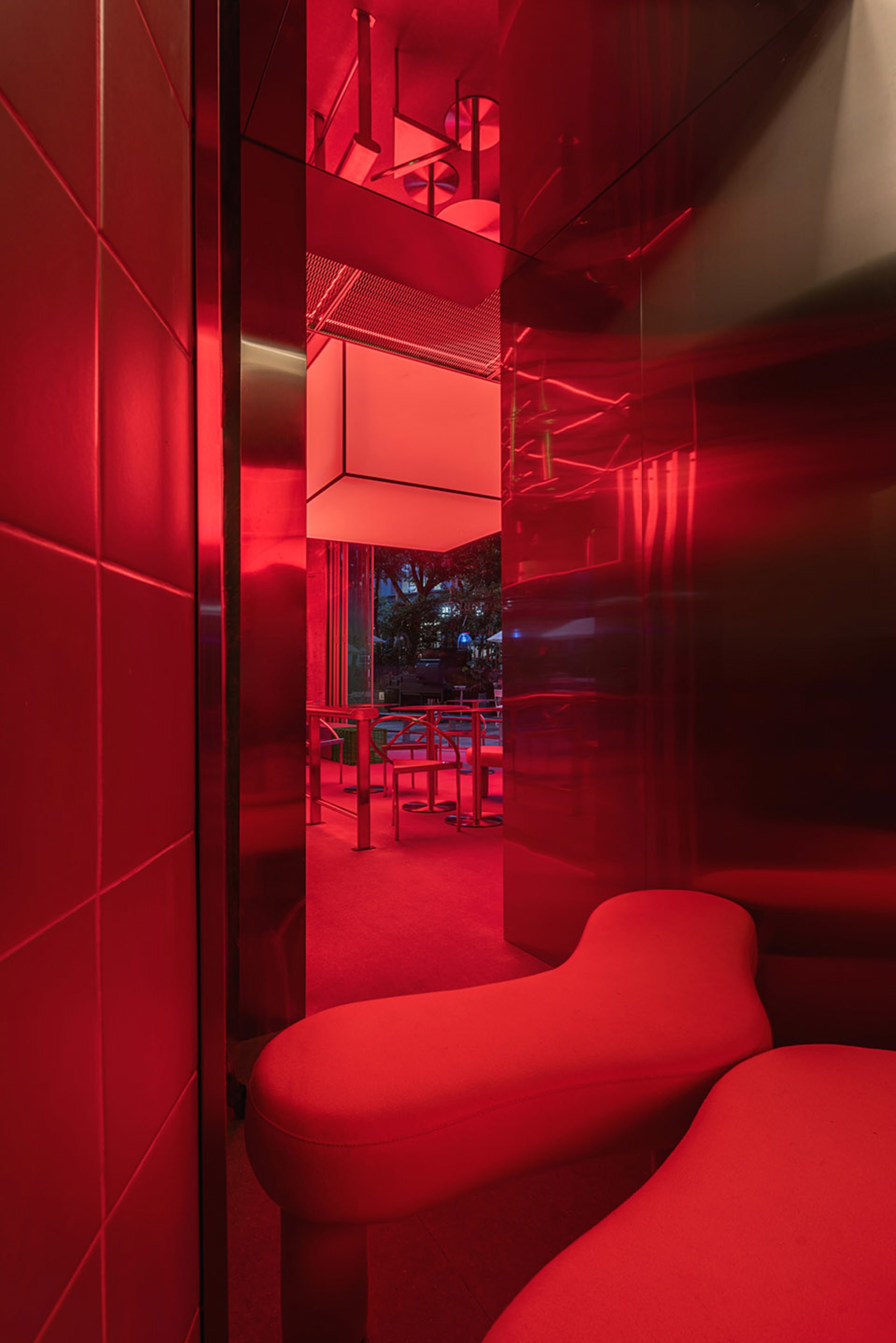 A minimalist interior design with red glass walls and furniture.