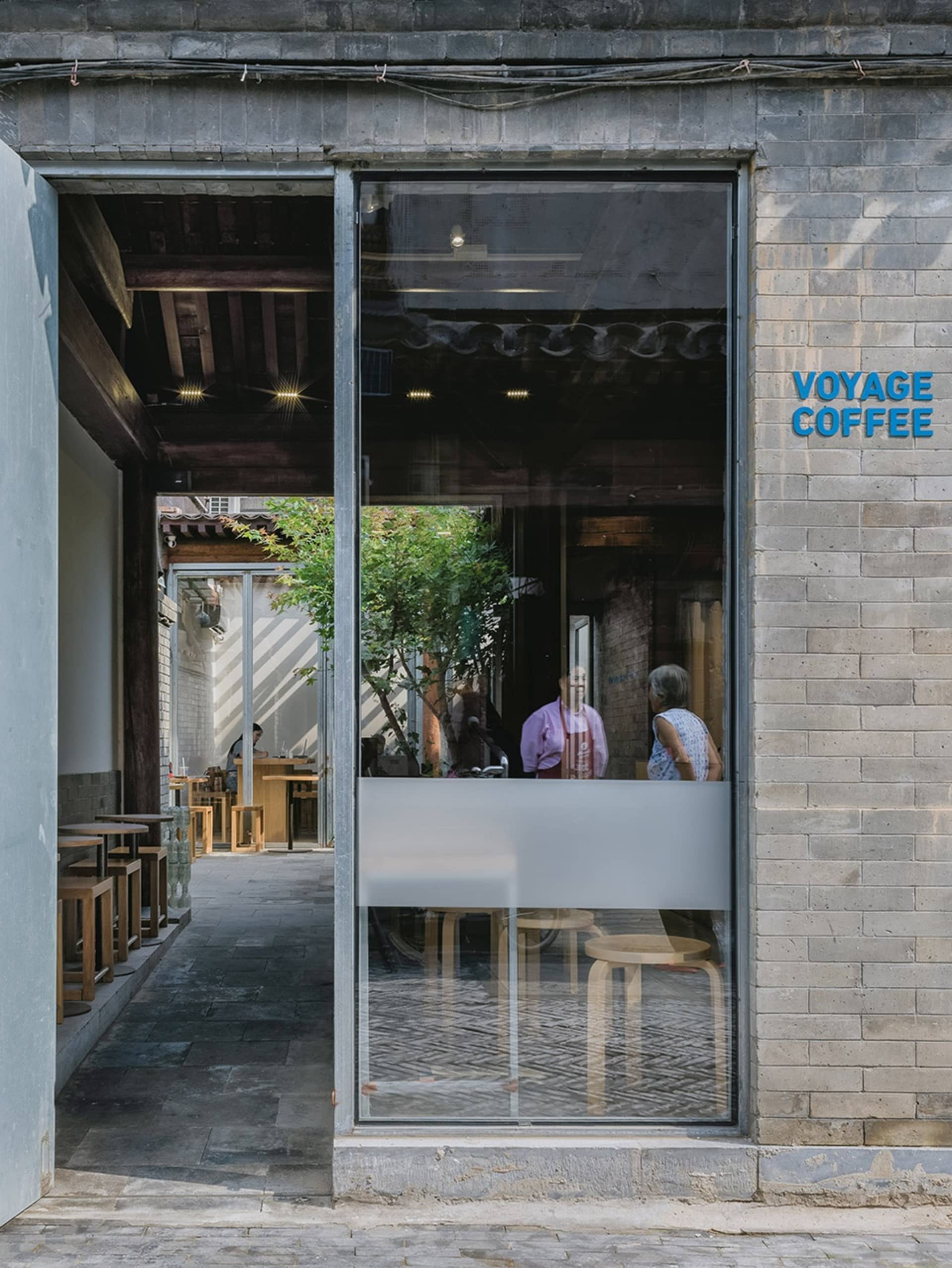 Voyage Coffee Shop with brick exterior, wooden stools, and glass doors.