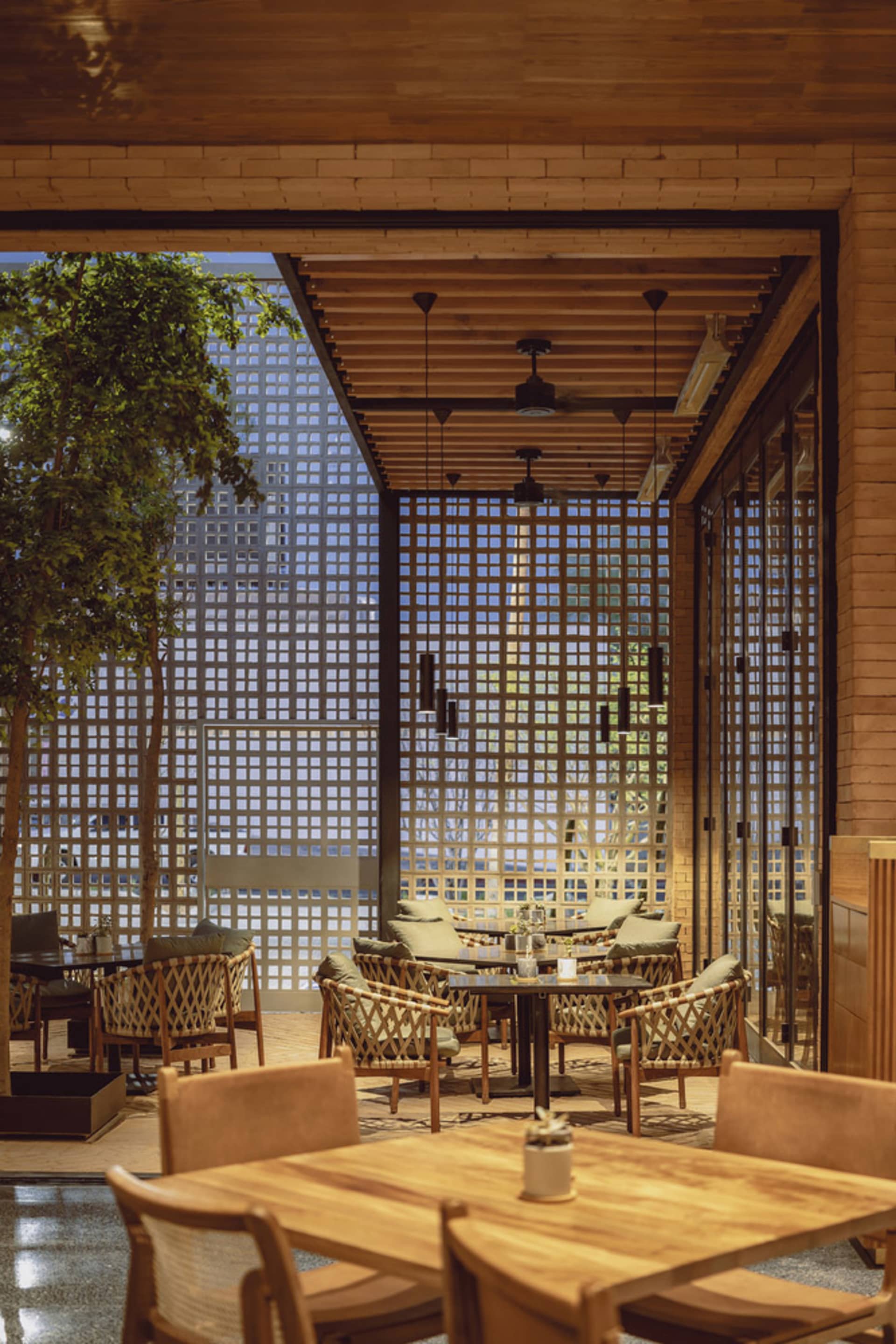 Indoor restaurant space featuring woven furniture with a wood frame and wooden ceiling beams.