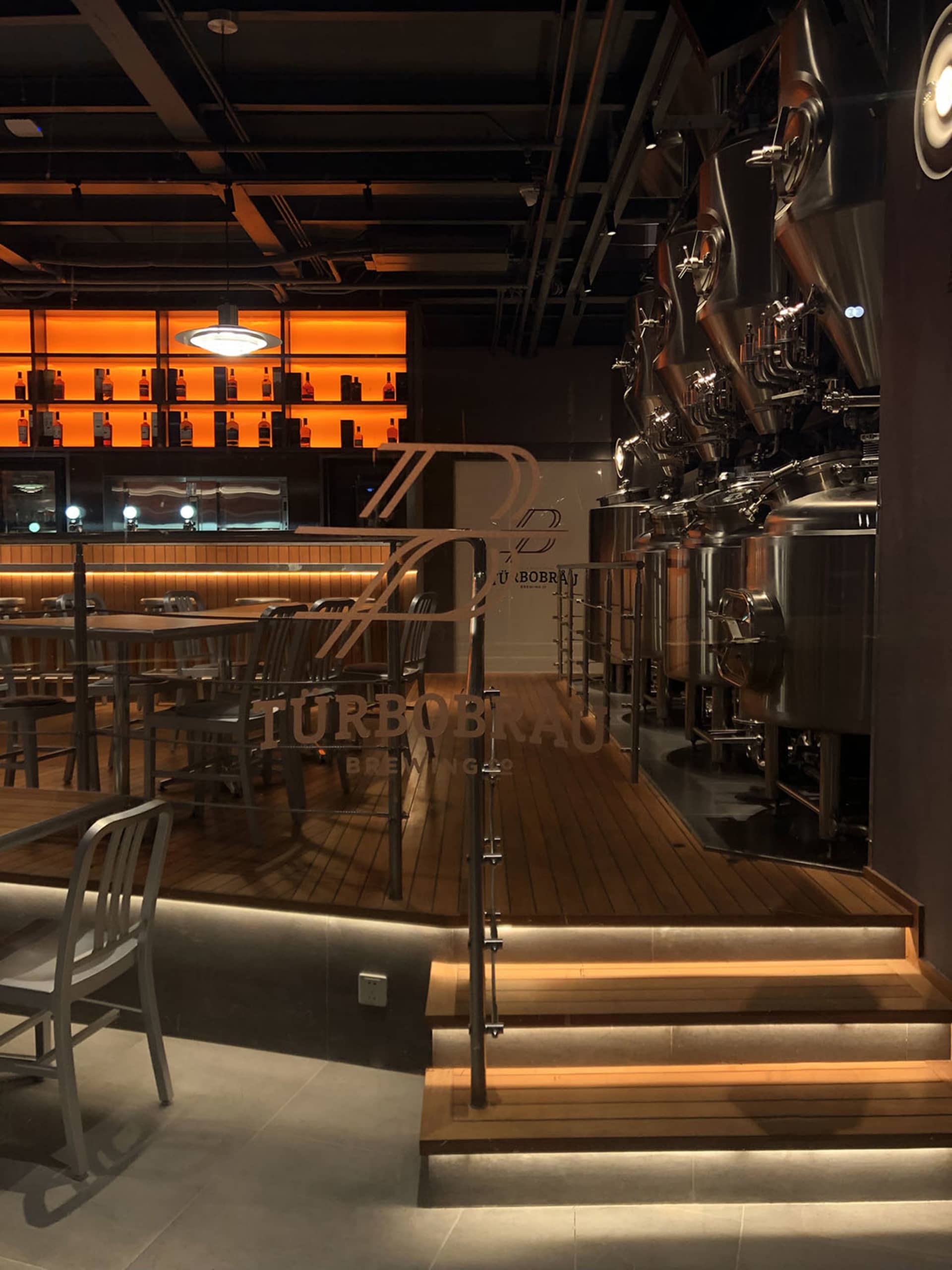 Contemporary brewery featuring steel brewing equipment and wooden bar seating.