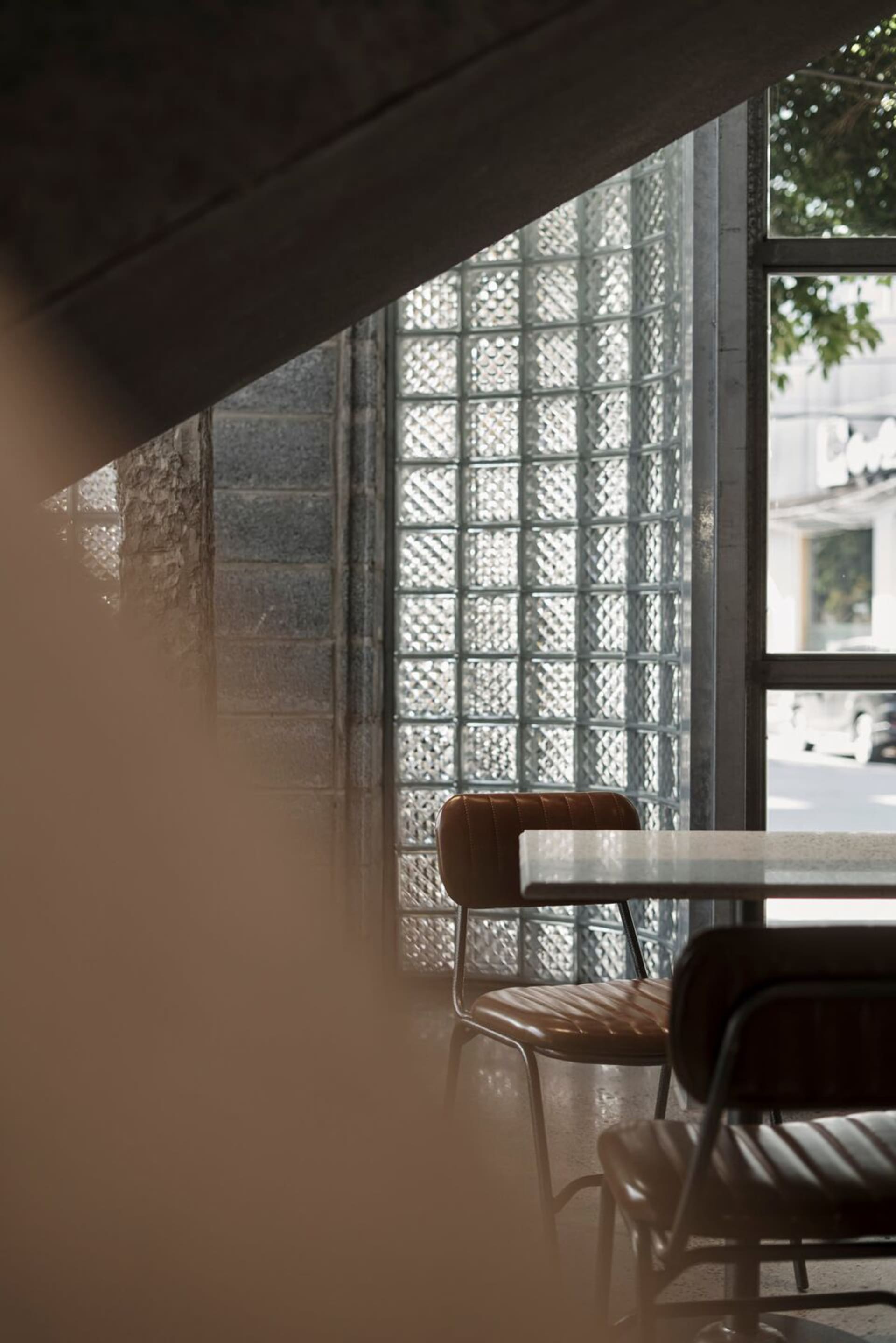 Modern cafe interior featuring glass block wall and concrete detailing.