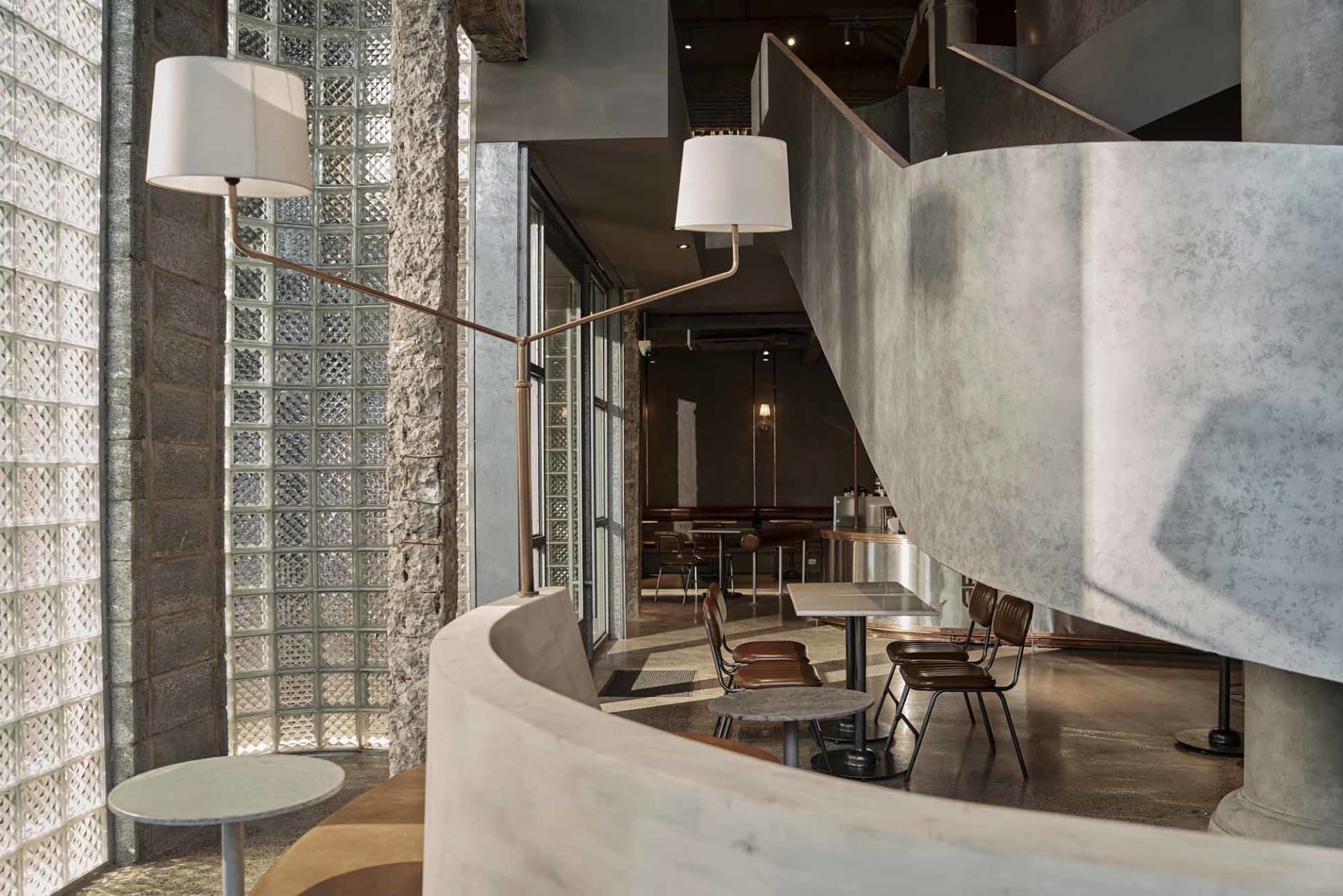 Interior of a modern industrial coffee shop featuring concrete and glass materials.