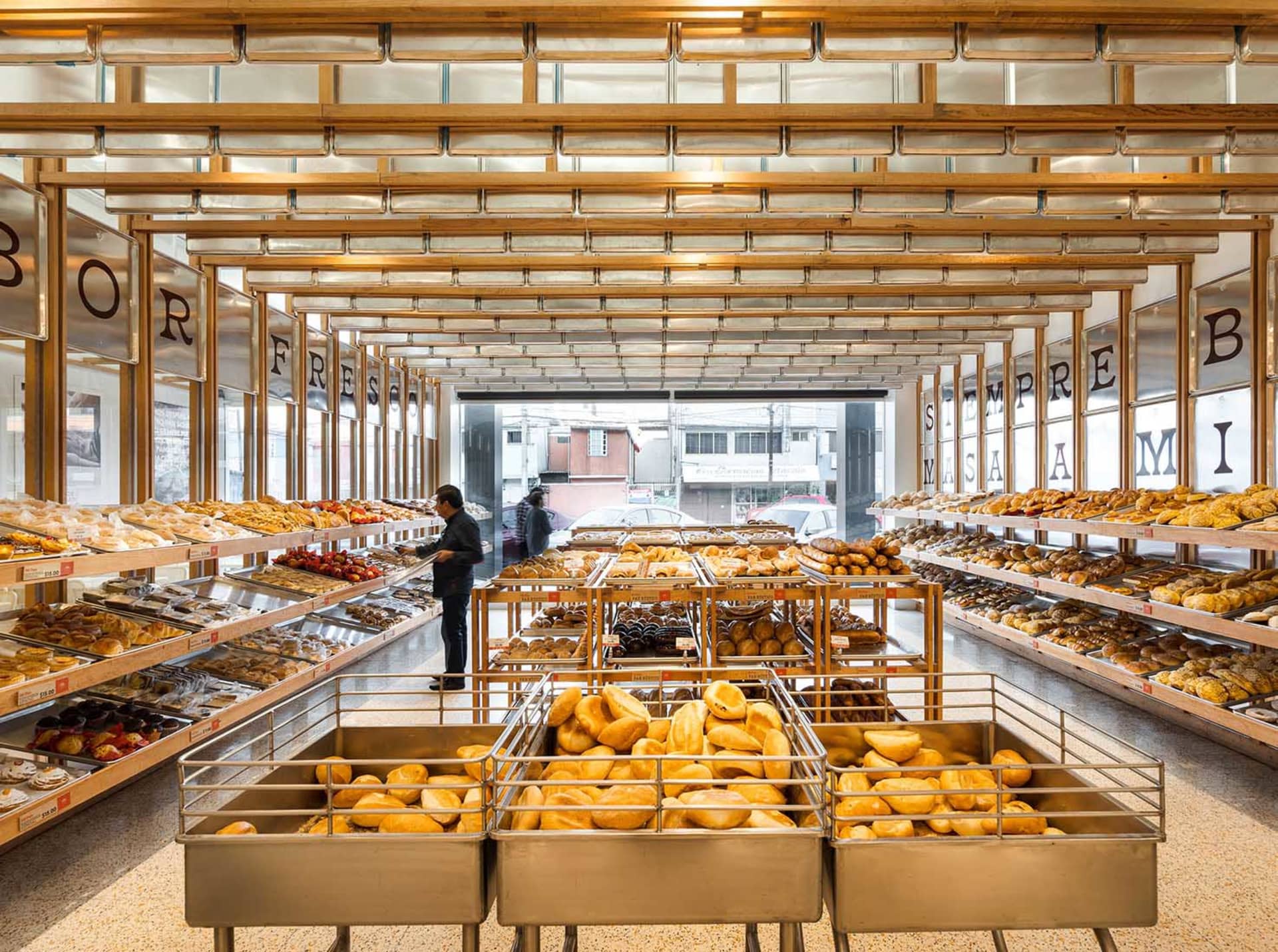 Modern bakery with wooden shelves and glass display cases filled with freshly baked goods.