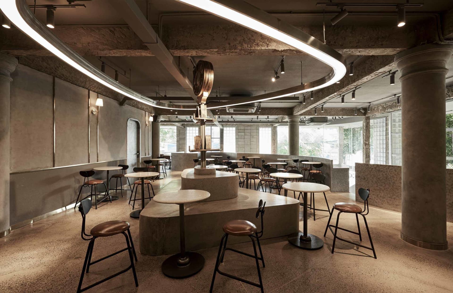 工業風設計的咖啡廳室內,設有混凝土柱與弧形燈具。