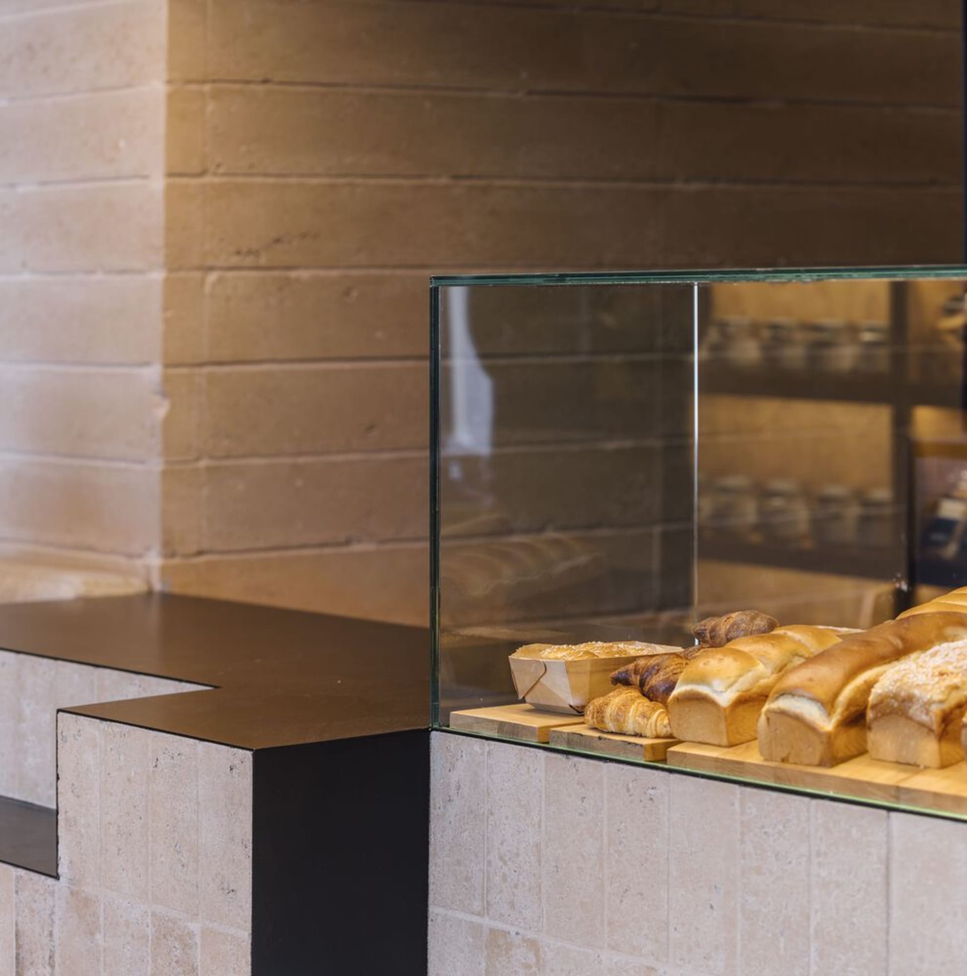 A sleek, modern glass bakery counter displaying various freshly baked breads and pastries.