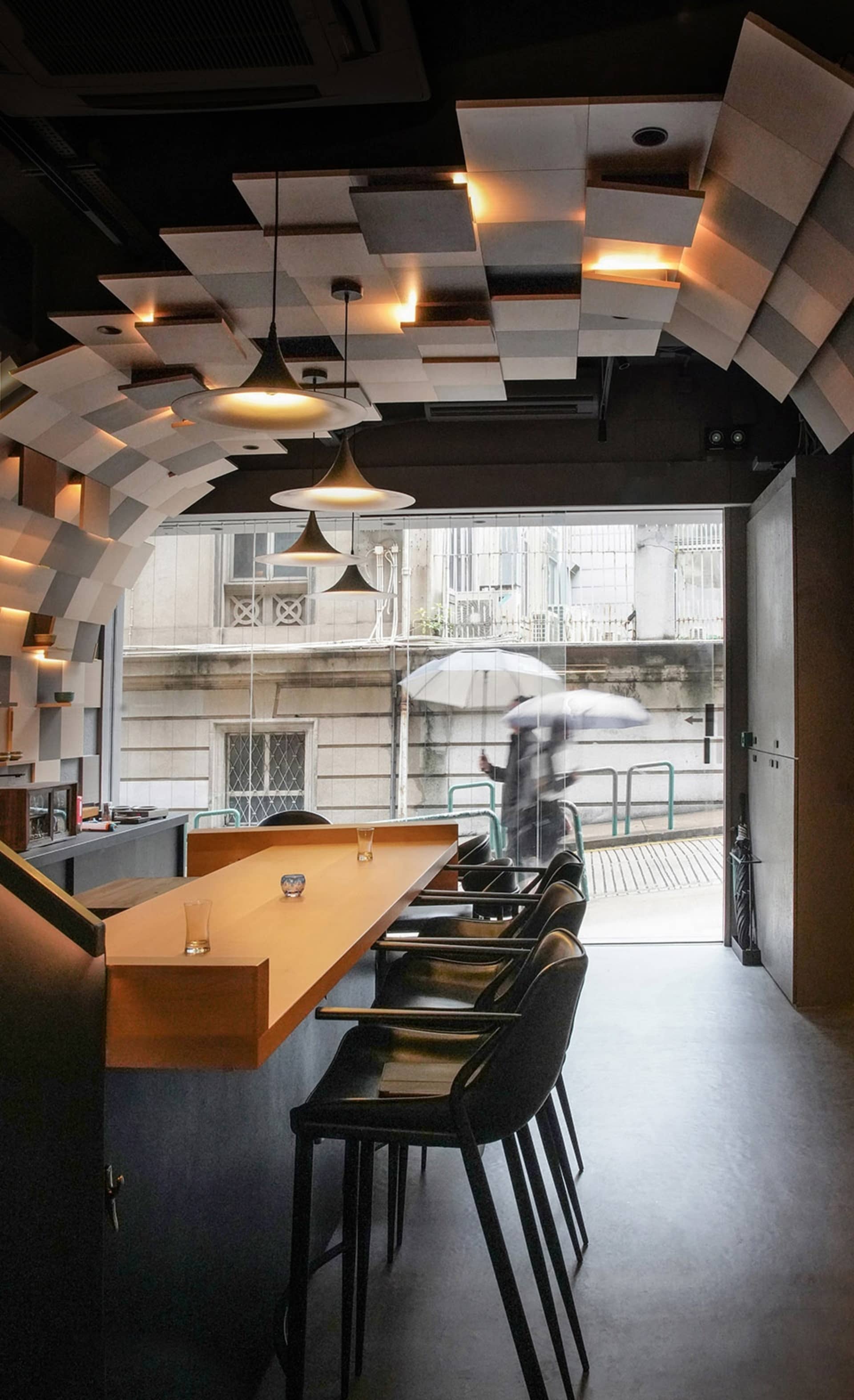 Industrial-style coffee shop bar with concrete materials, pendant lighting, and high stools.