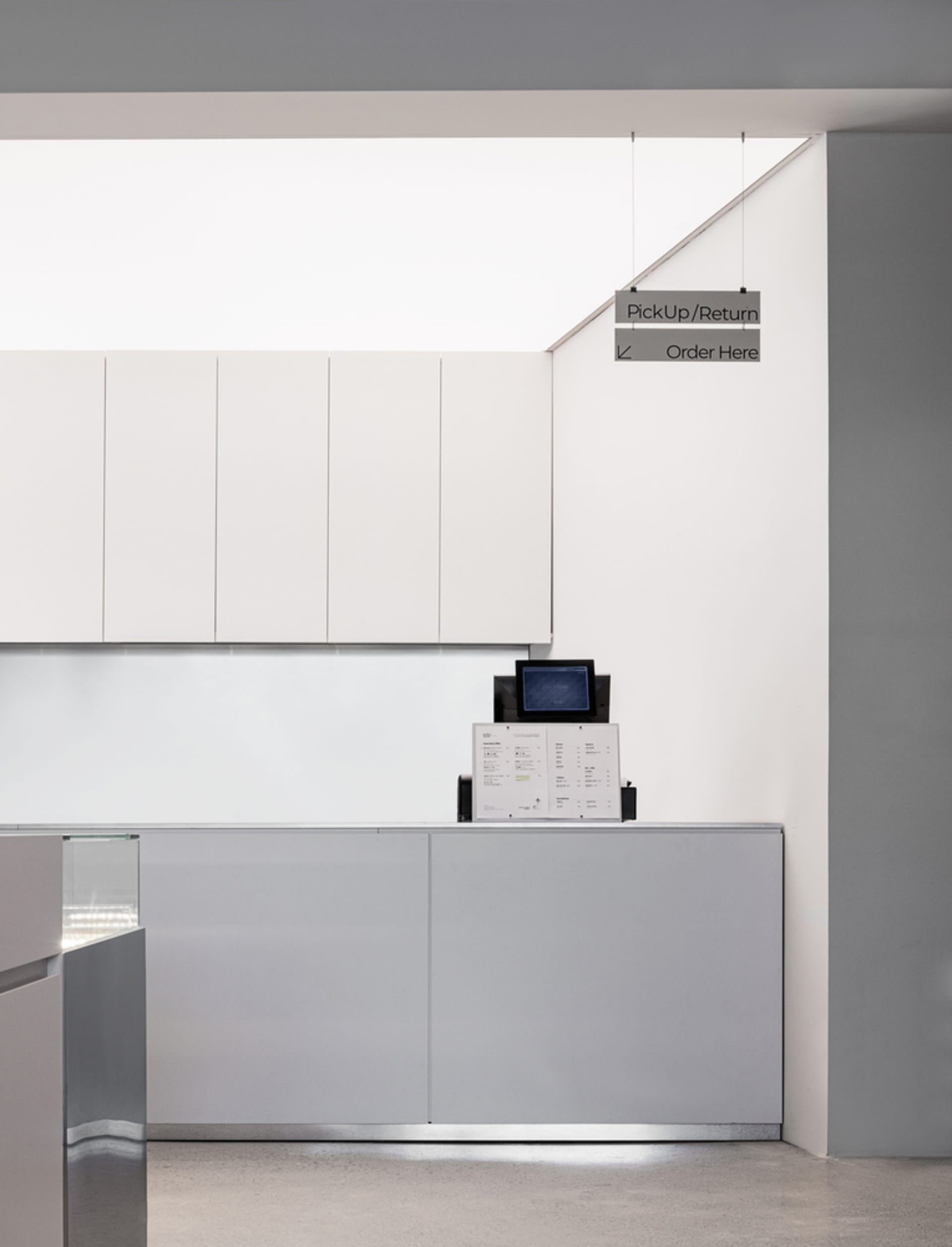 Minimalistic design of a café counter featuring glass materials and sleek lines.