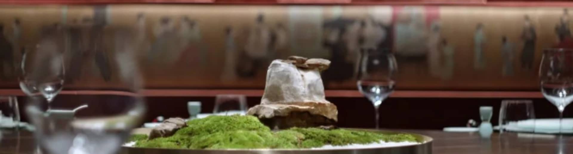 A table centerpiece featuring moss and a decorative element in a restaurant setting.