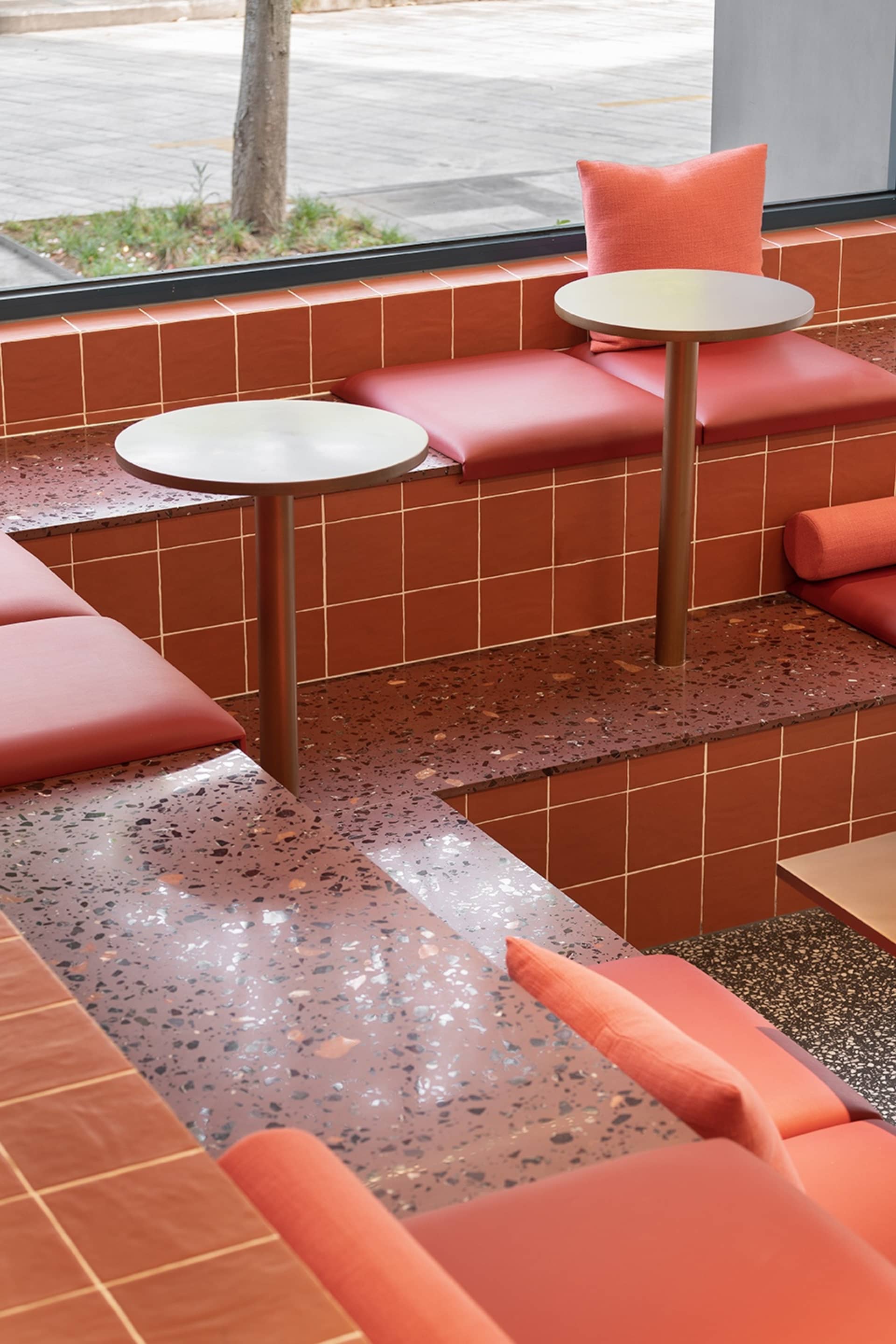 Modern cafe seating with red cushions on a terrazzo floor and table.