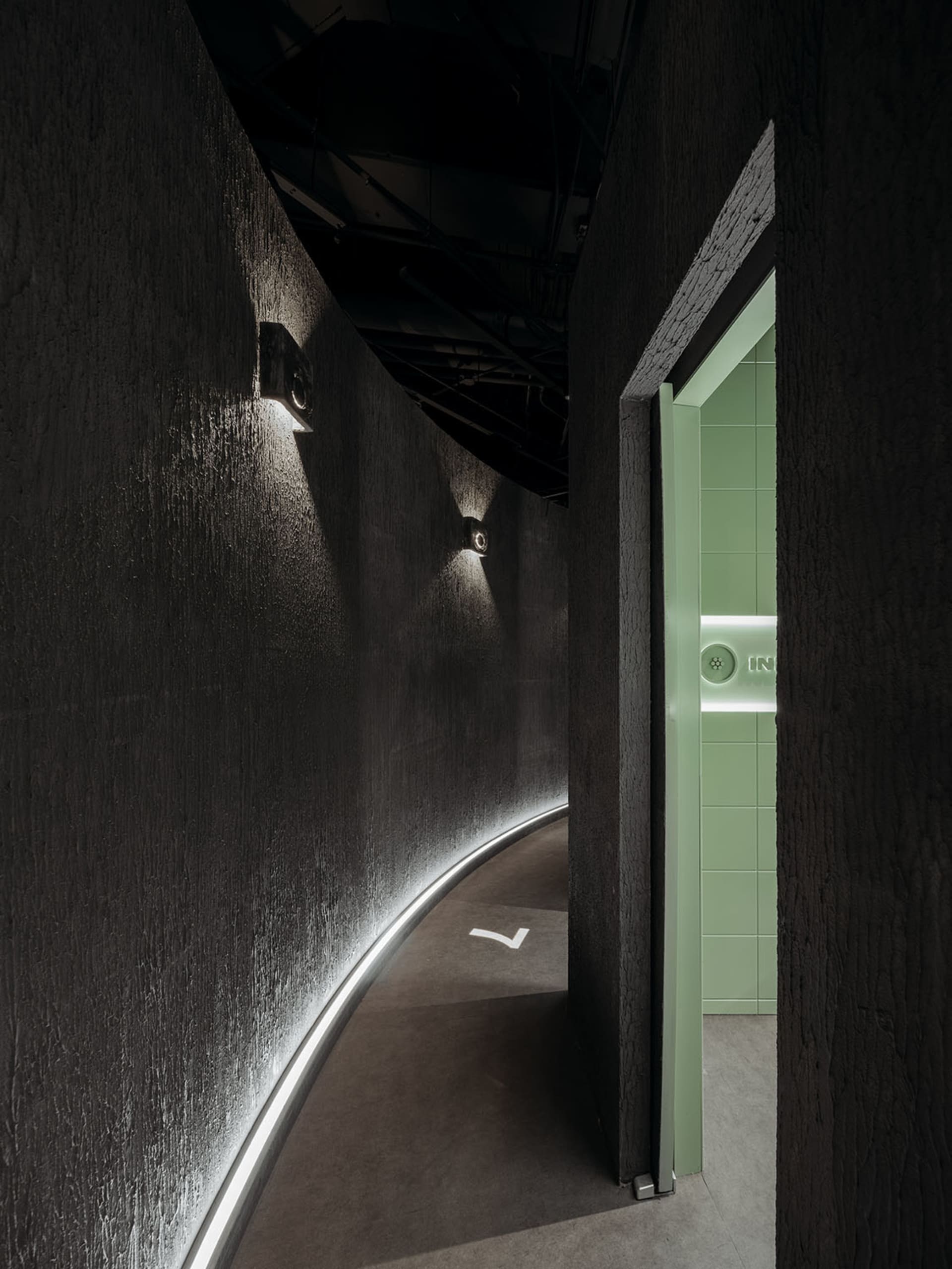 Modern interior design featuring a corner wall with textured concrete finish, illuminated by subtle ambient lighting from emb