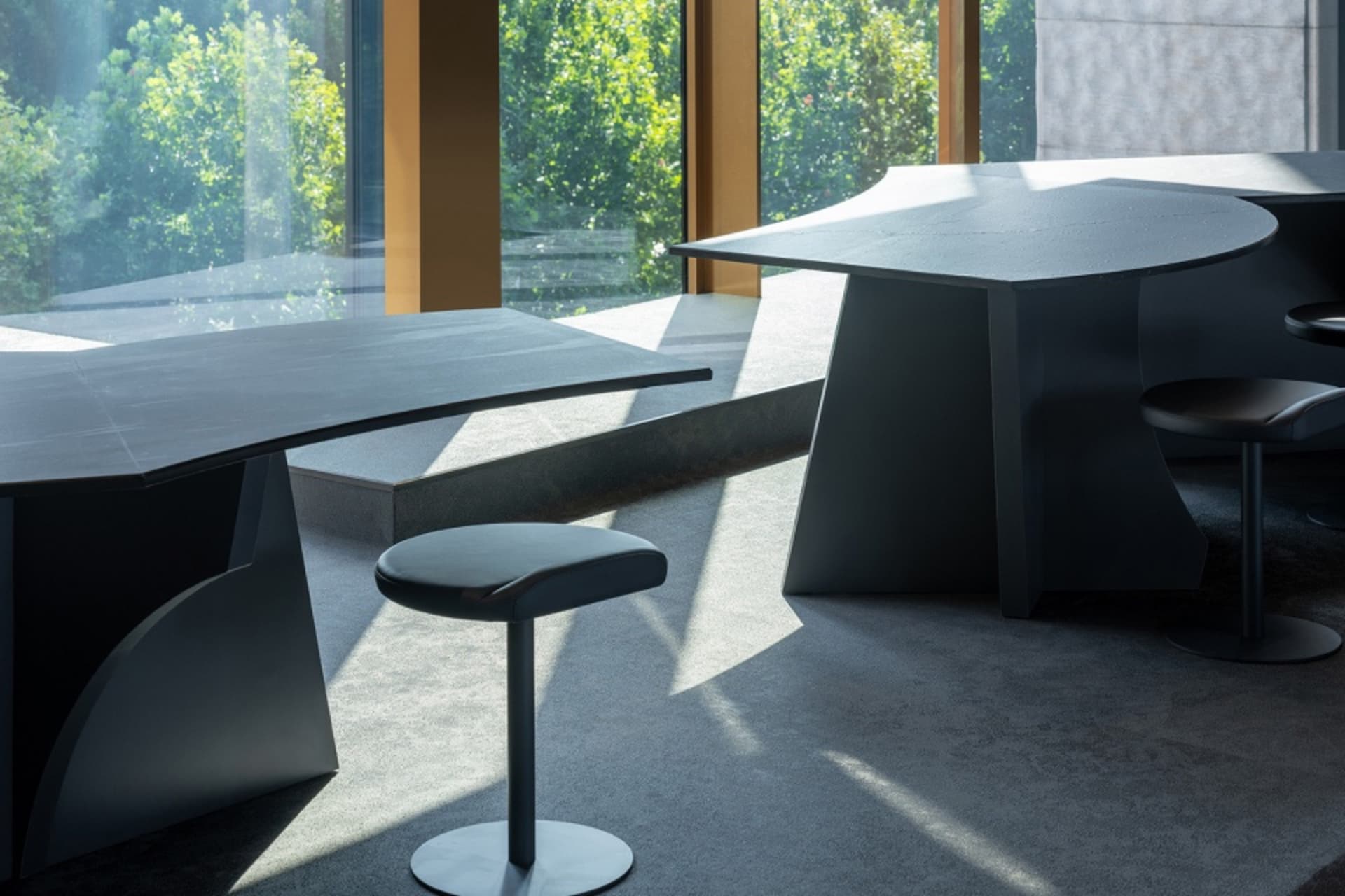 Modern desk with matching stools featuring metallic legs and a leather seat.