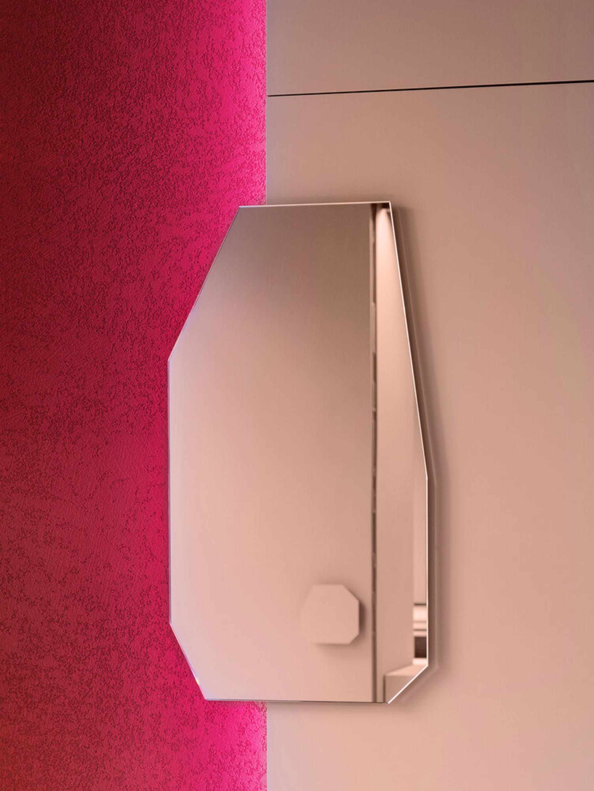A sleek, metallic mirror mounted on a textured wall