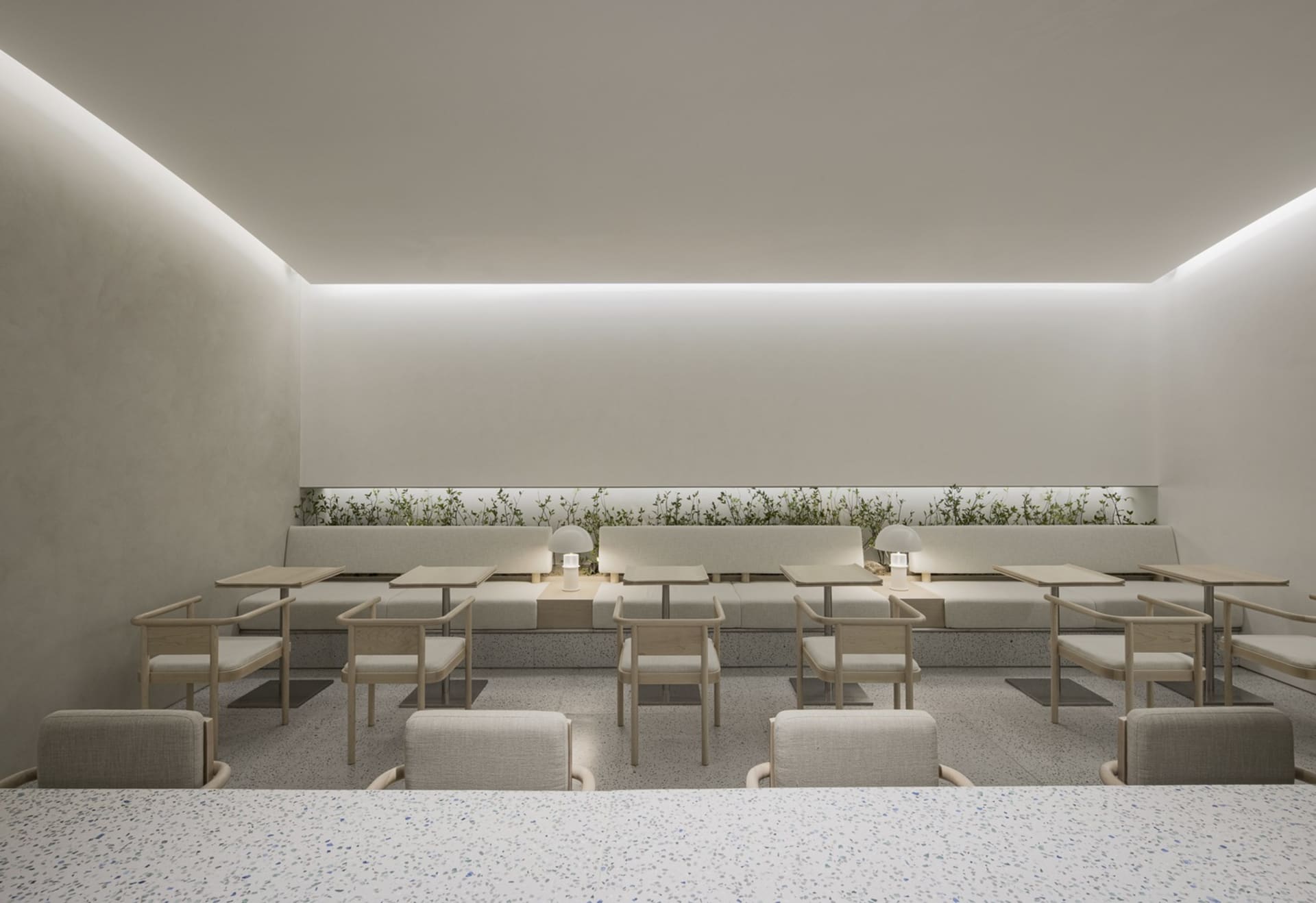 Modern minimalist restaurant interior with terrazzo flooring and seating.