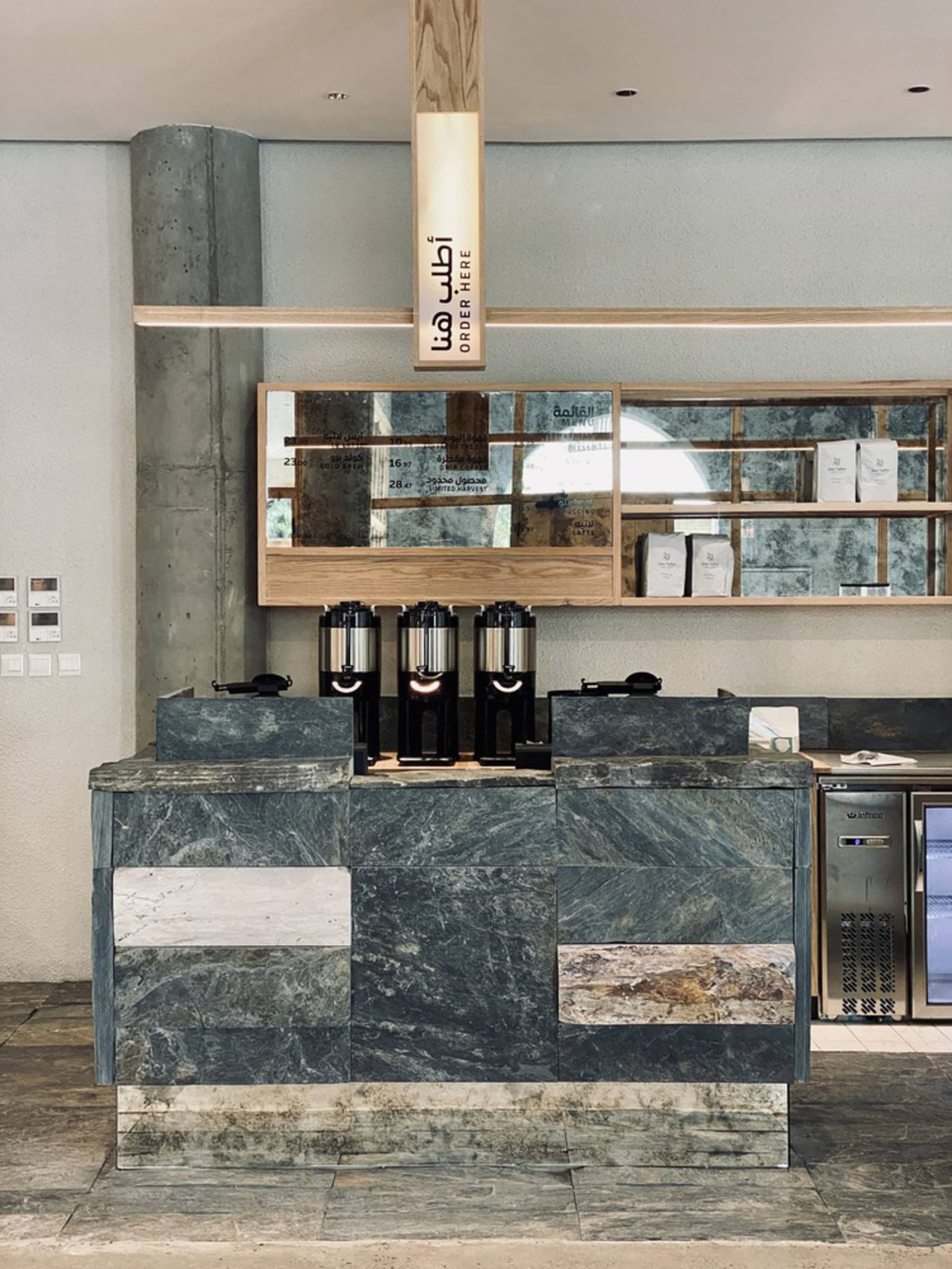 An image of a modern coffee shop interior with a marble and concrete counter.