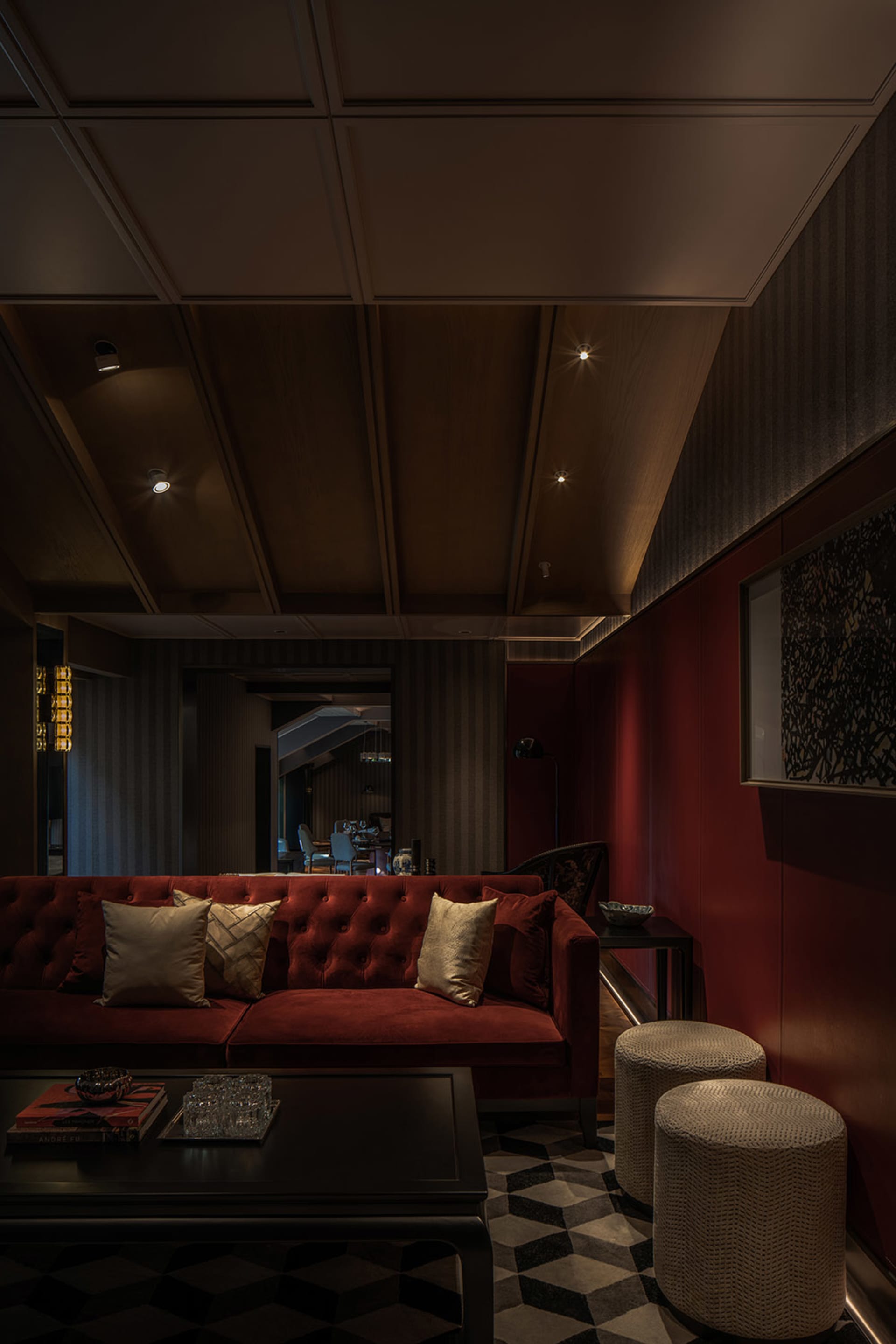 A modern living room featuring a red couch with gold and red cushions, accompanied by a dark coffee table and geometric patte