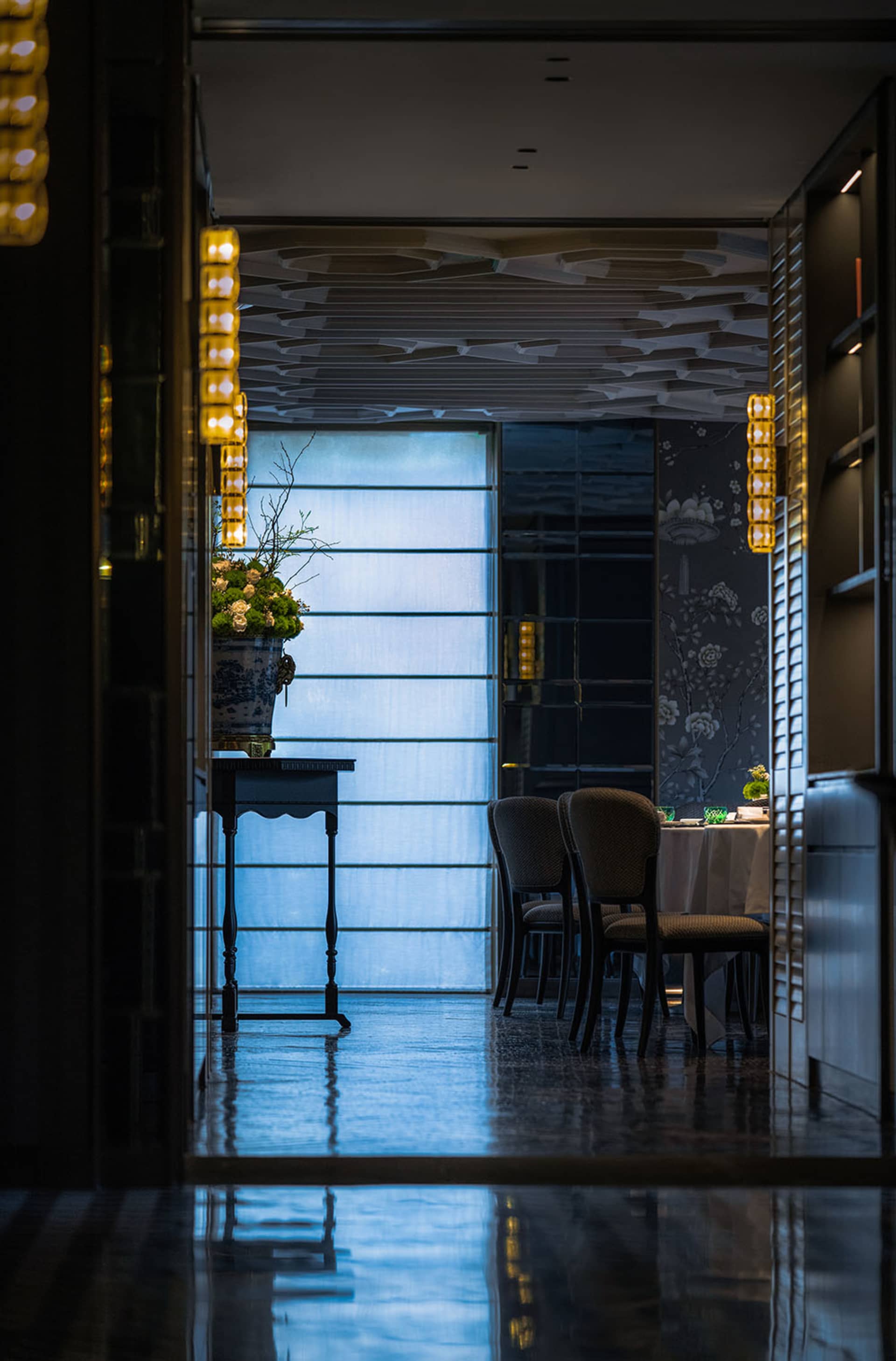 Modern restaurant interior with glass, metal, and wooden decor and lighting.