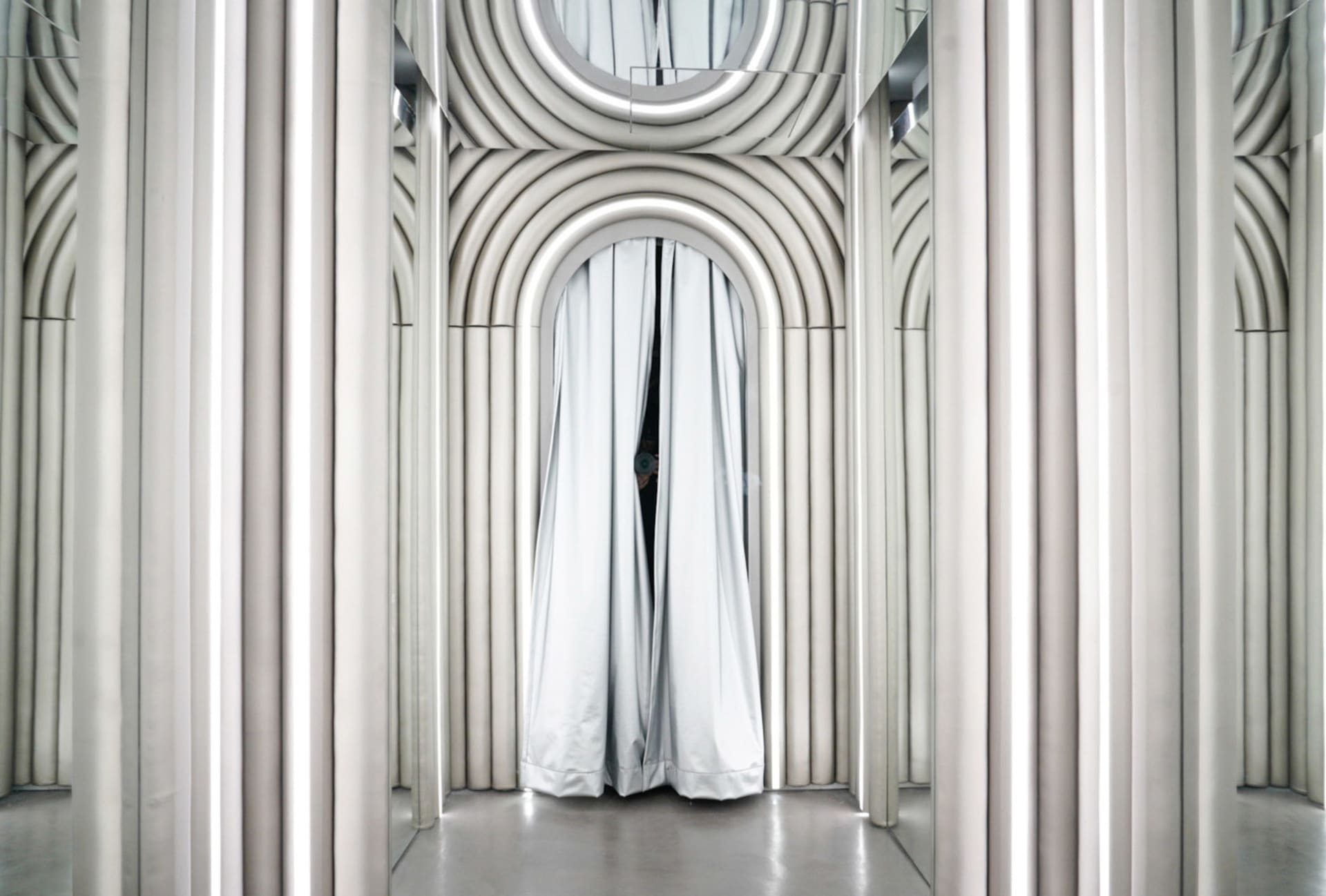 A minimalist interior design featuring a white curtain with arched arches and reflective surfaces.
