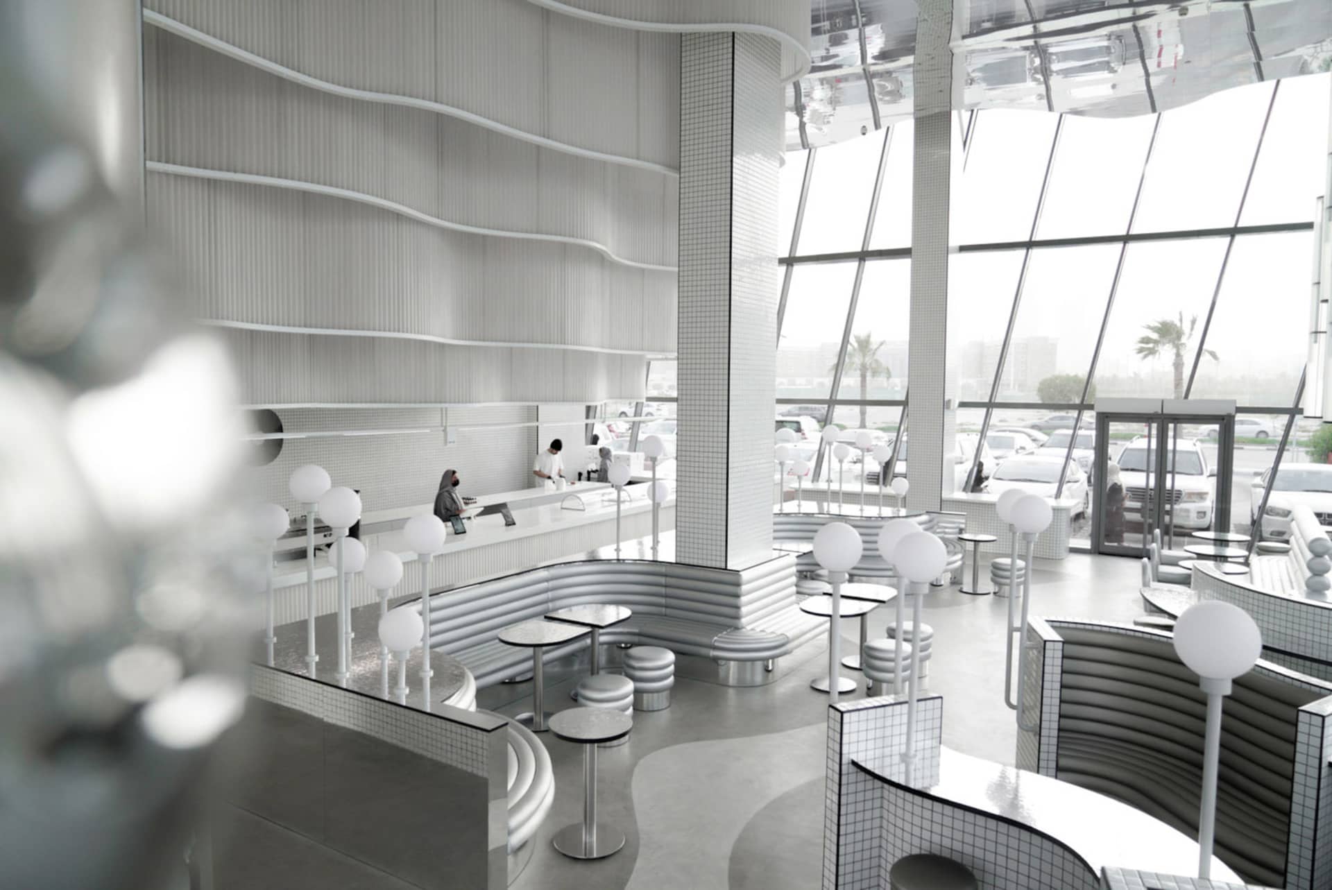 A modern, minimalist restaurant interior with metallic tile walls and a spacious, open design.