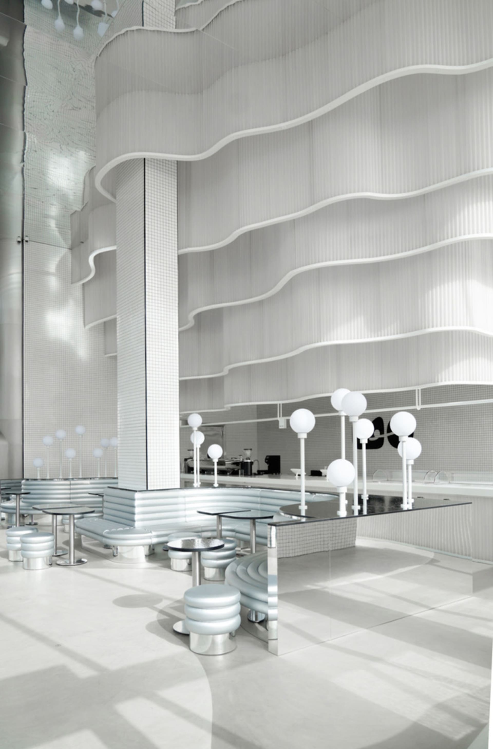A modern coffee shop featuring a metallic counter with a sleek, minimalist design.